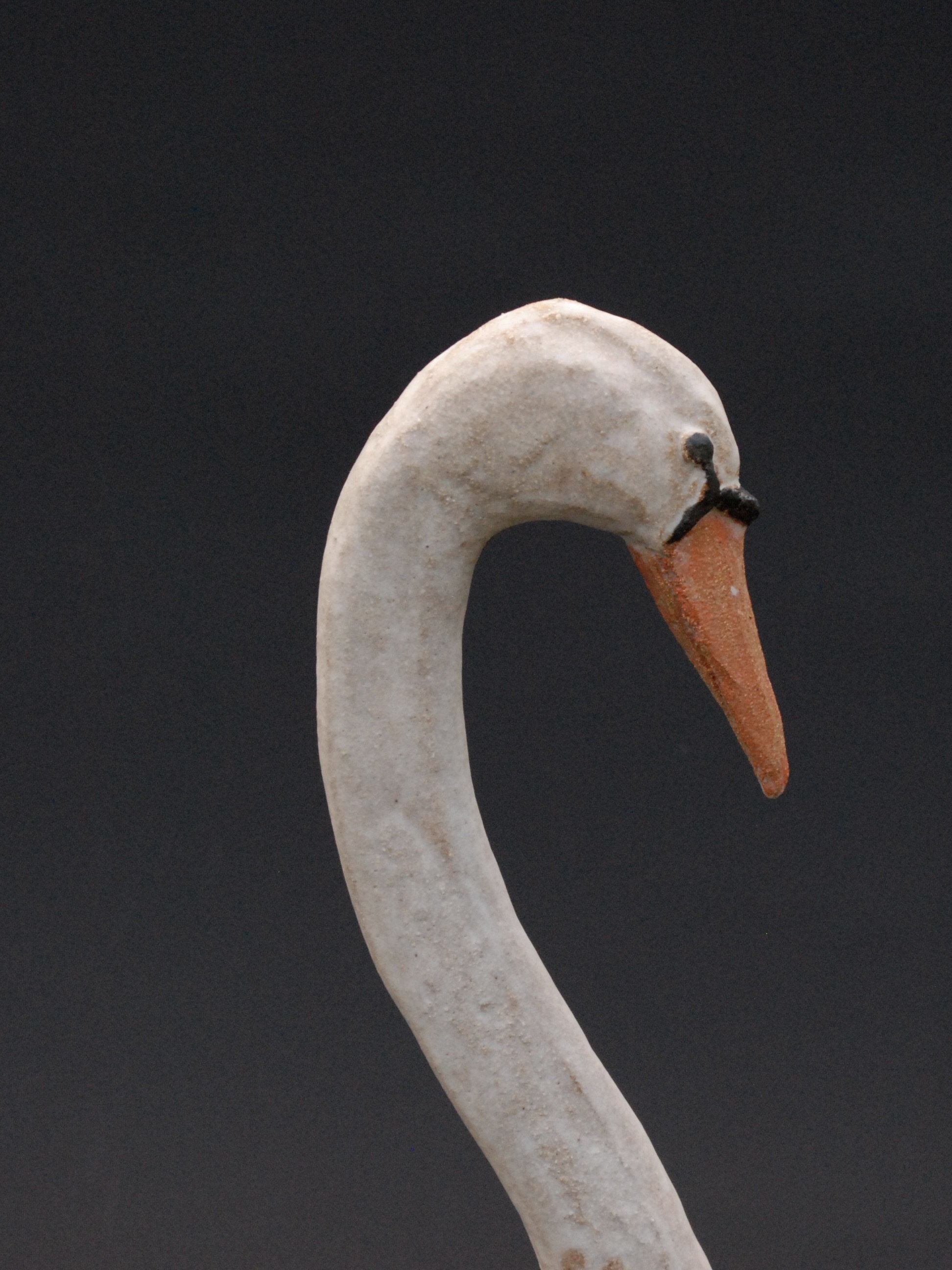 Image shows a large ceramic swan, covered in a white glaze with an orange beak. The swan has an particularly long neck in proportion to its body