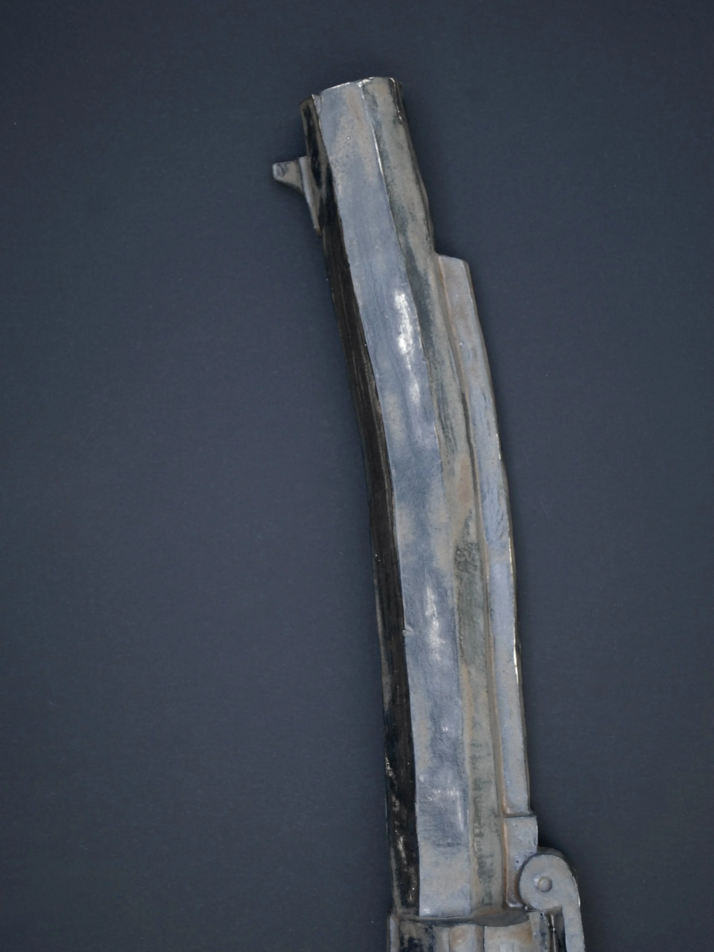 Image shows a ceramic, antique style revolver with a bent barrel. The gun has a dark weathered finish on the metal contrasting with the painted wooden style grip