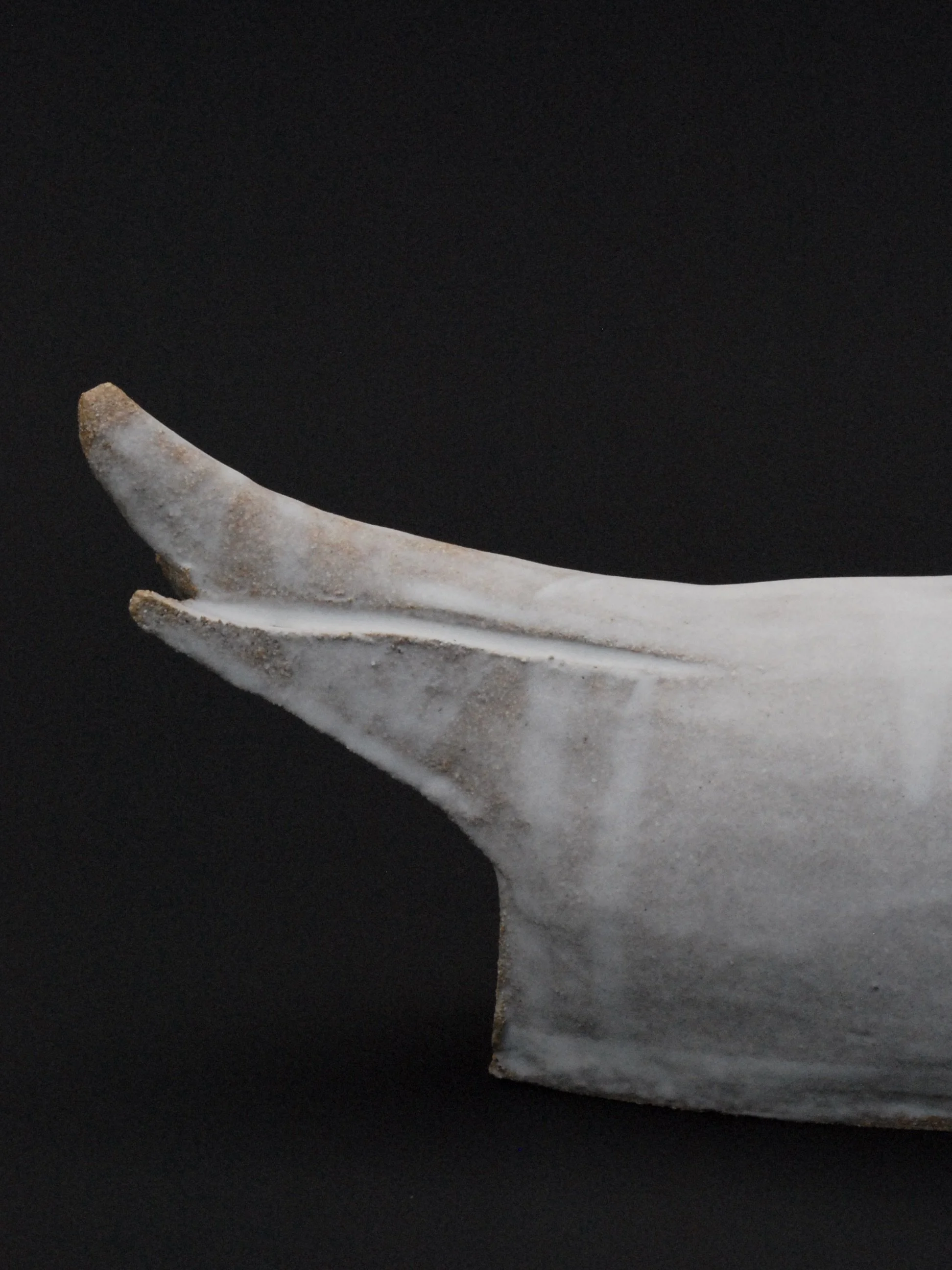 Image shows a large ceramic swan, covered in a white glaze with an orange beak. The swan has an particularly long neck in proportion to its body
