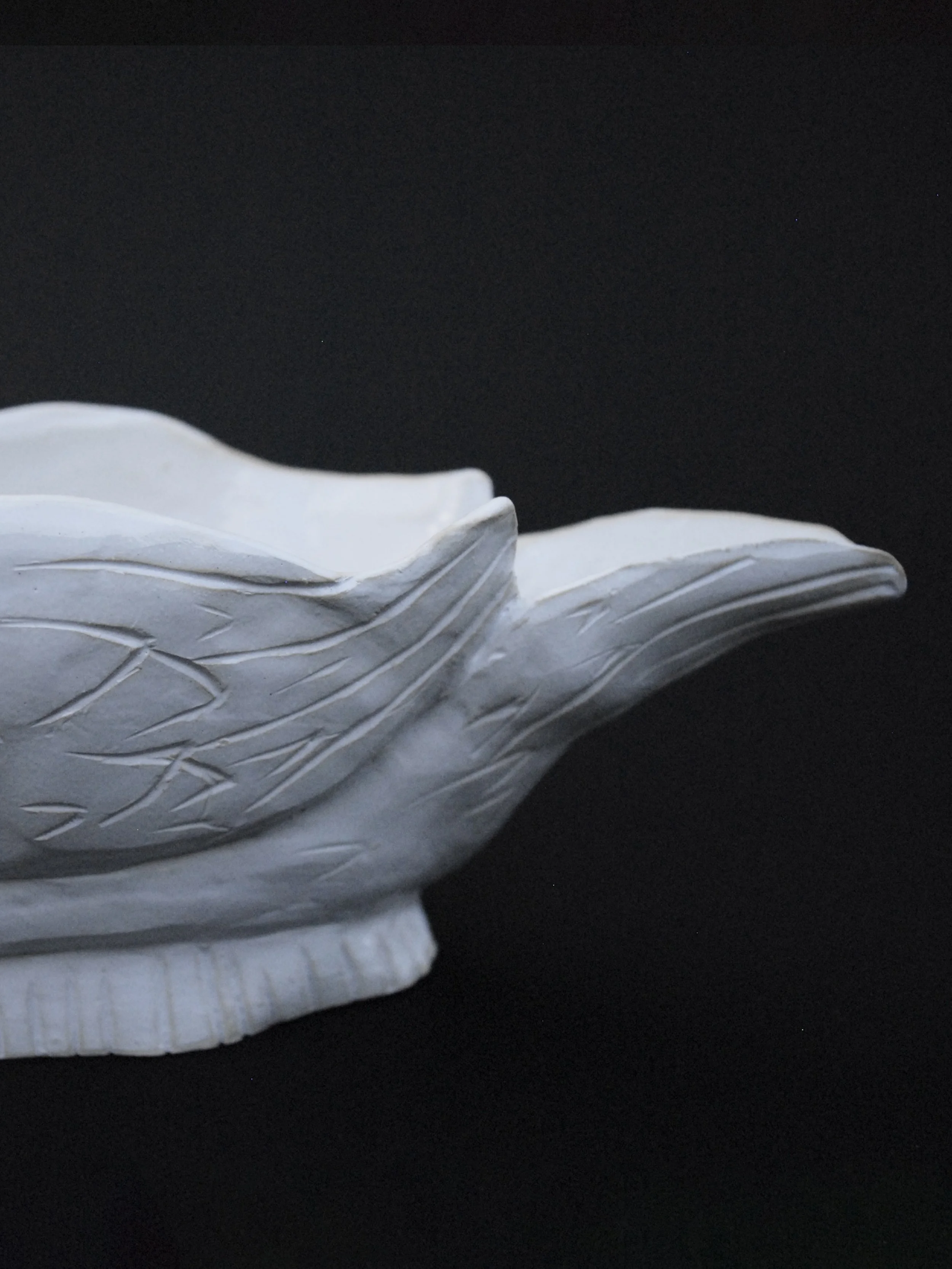 Image shows a ceramic hand-sculpted, swan shaped gravy boat, covered in white glaze and delicate details, it has carved feathers and a long neck which acts as the handle
