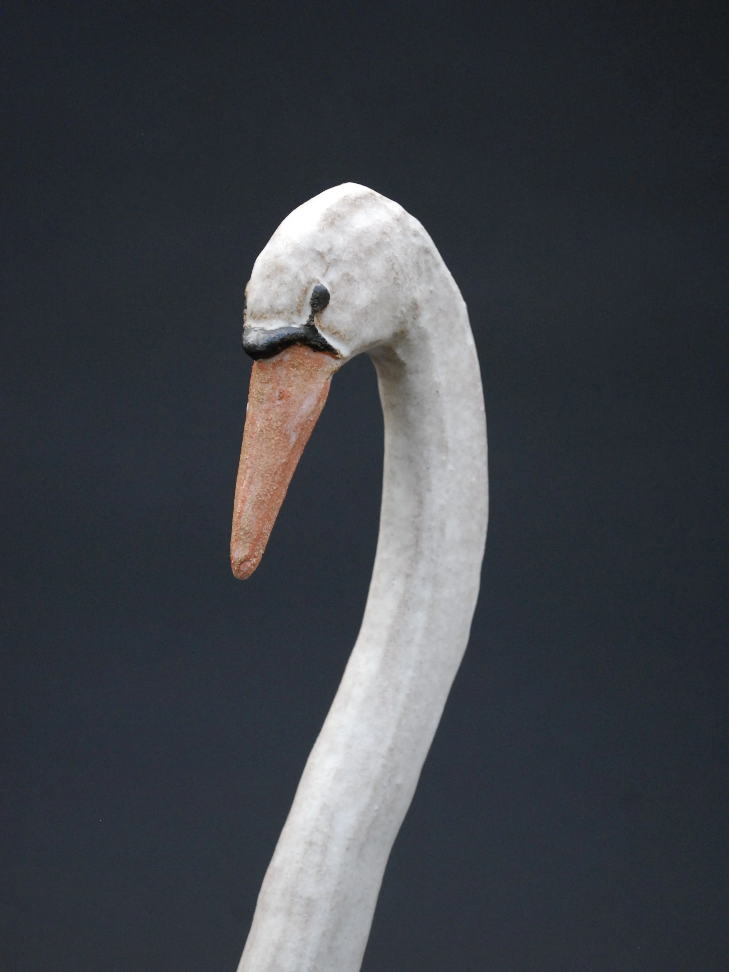 Image shows a large ceramic swan, covered in a white glaze with an orange beak. The swan has an particularly long neck in proportion to its body