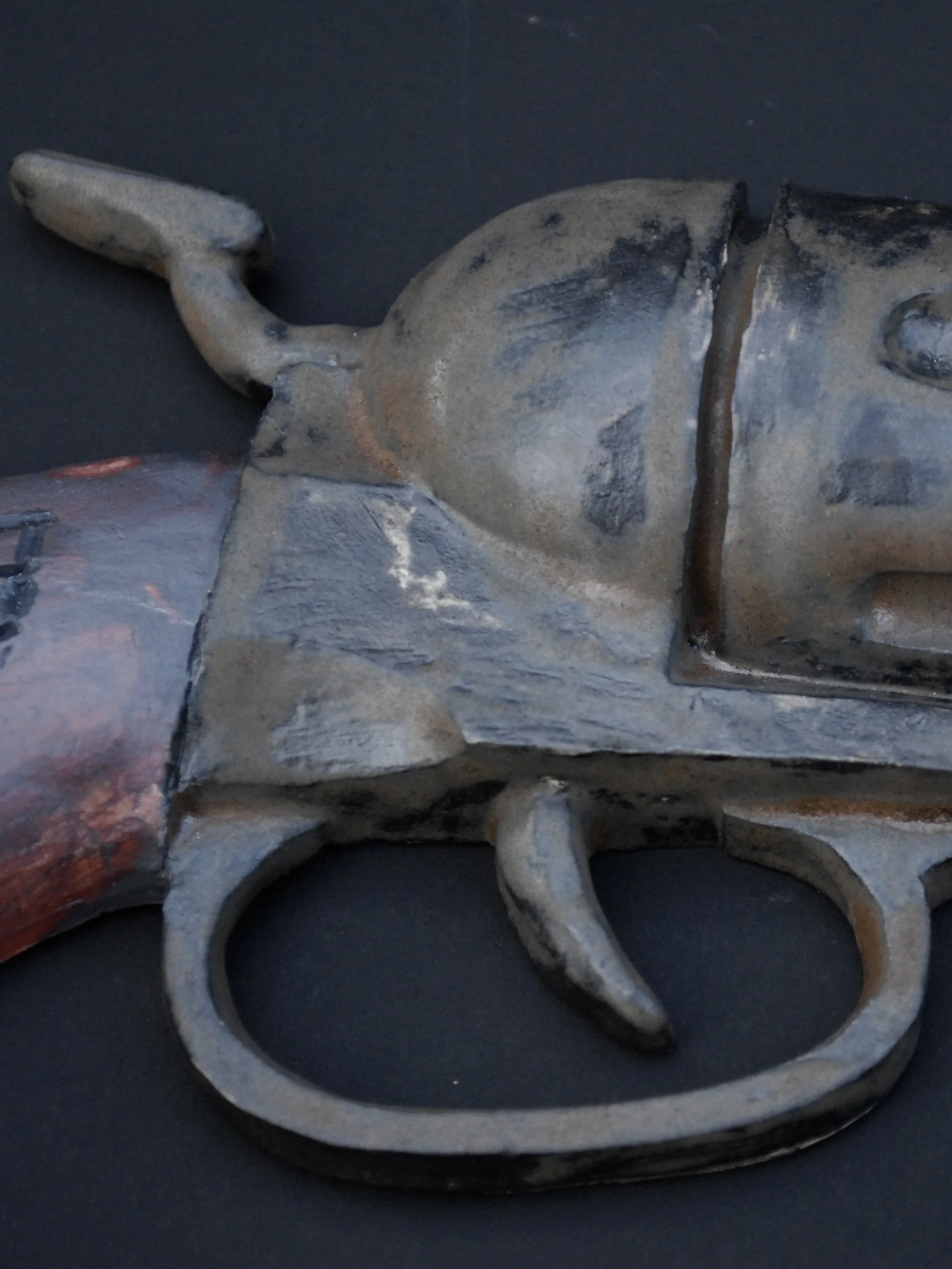 Image shows a ceramic, antique style revolver with a bent barrel. The gun has a dark weathered finish on the metal contrasting with the painted wooden style grip