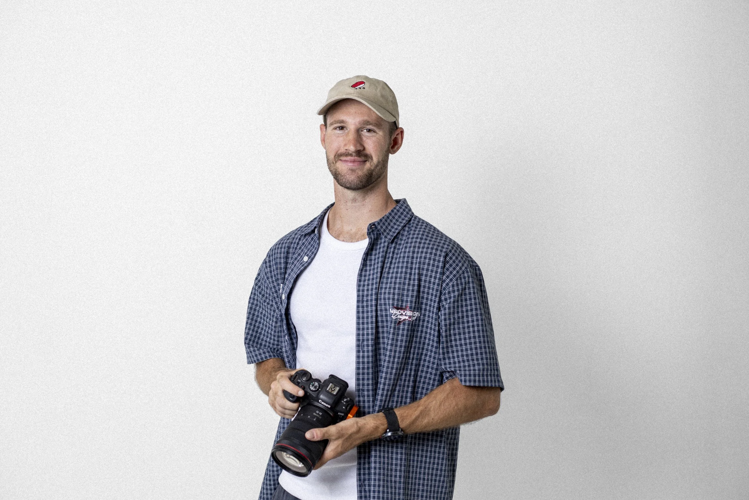 Man wearing a plaid shirt and hat holding a camera