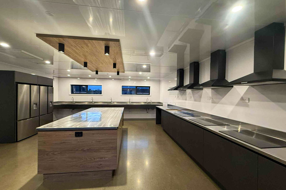 Modern kitchen with stainless steel appliances, black cabinets, and a large island with a marble top.