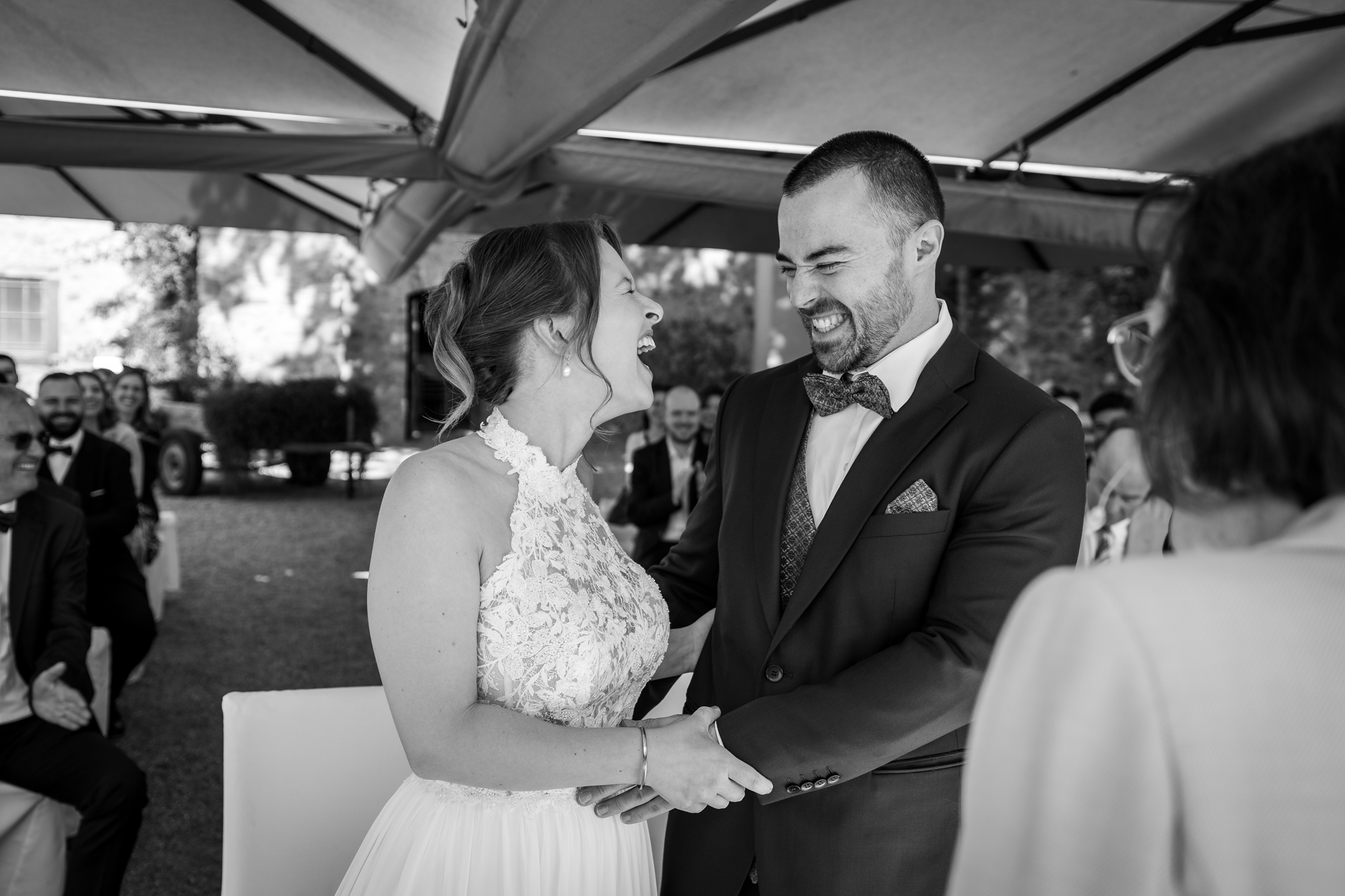 Braut und Bräutigam lachen während ihrer Hochzeit im Burgzwinger der Kurfürstlichen Burg in Eltville, umgeben von Gästen.