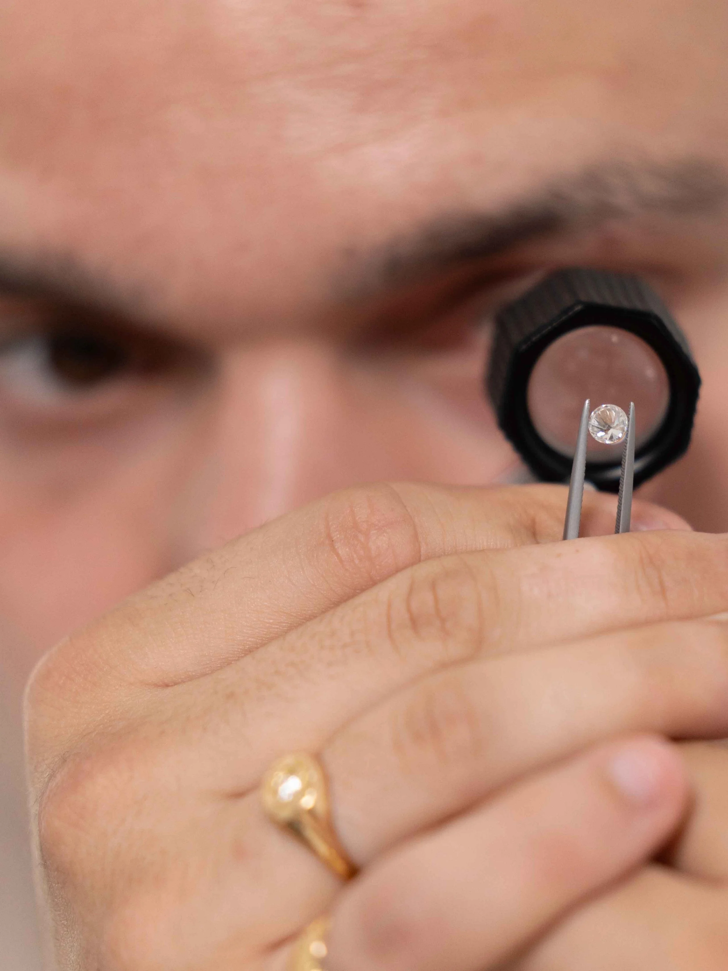 Pessoa examinando um diamante com uma lupa.