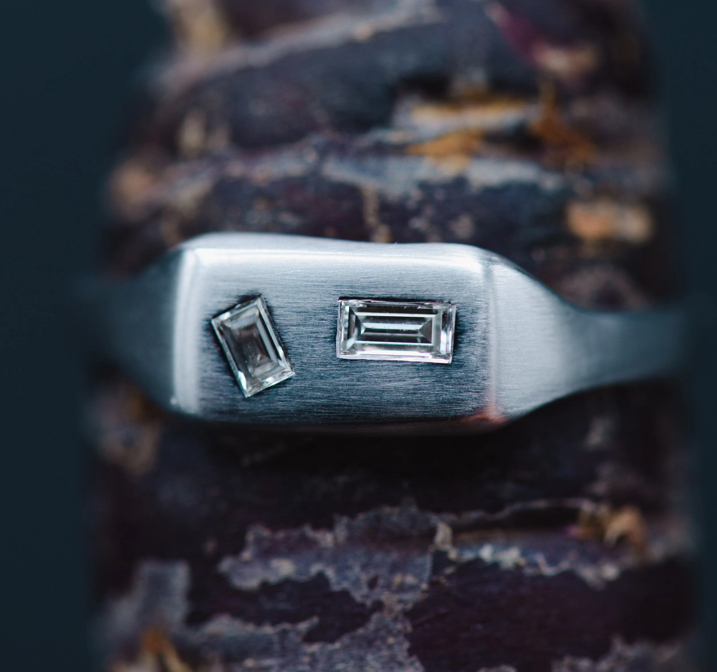 Nahaufnahme eines modernen Gold Rings mit zwei rechteckigen Diamanten, auf Holz verarbeitet