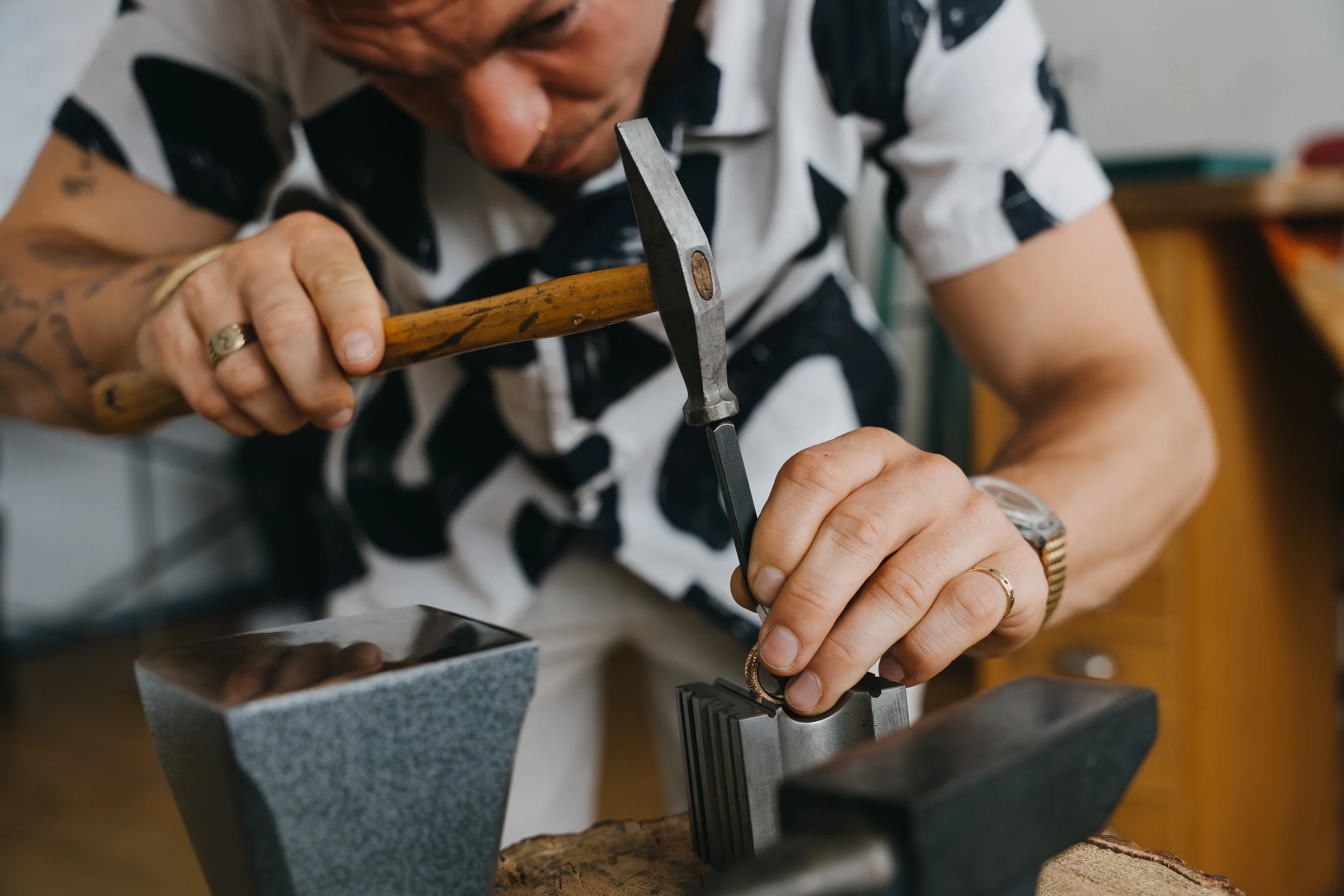 Max Sitte schlägt mit einem Hammer auf einen Metallgegenstand in einer Werkstatt.