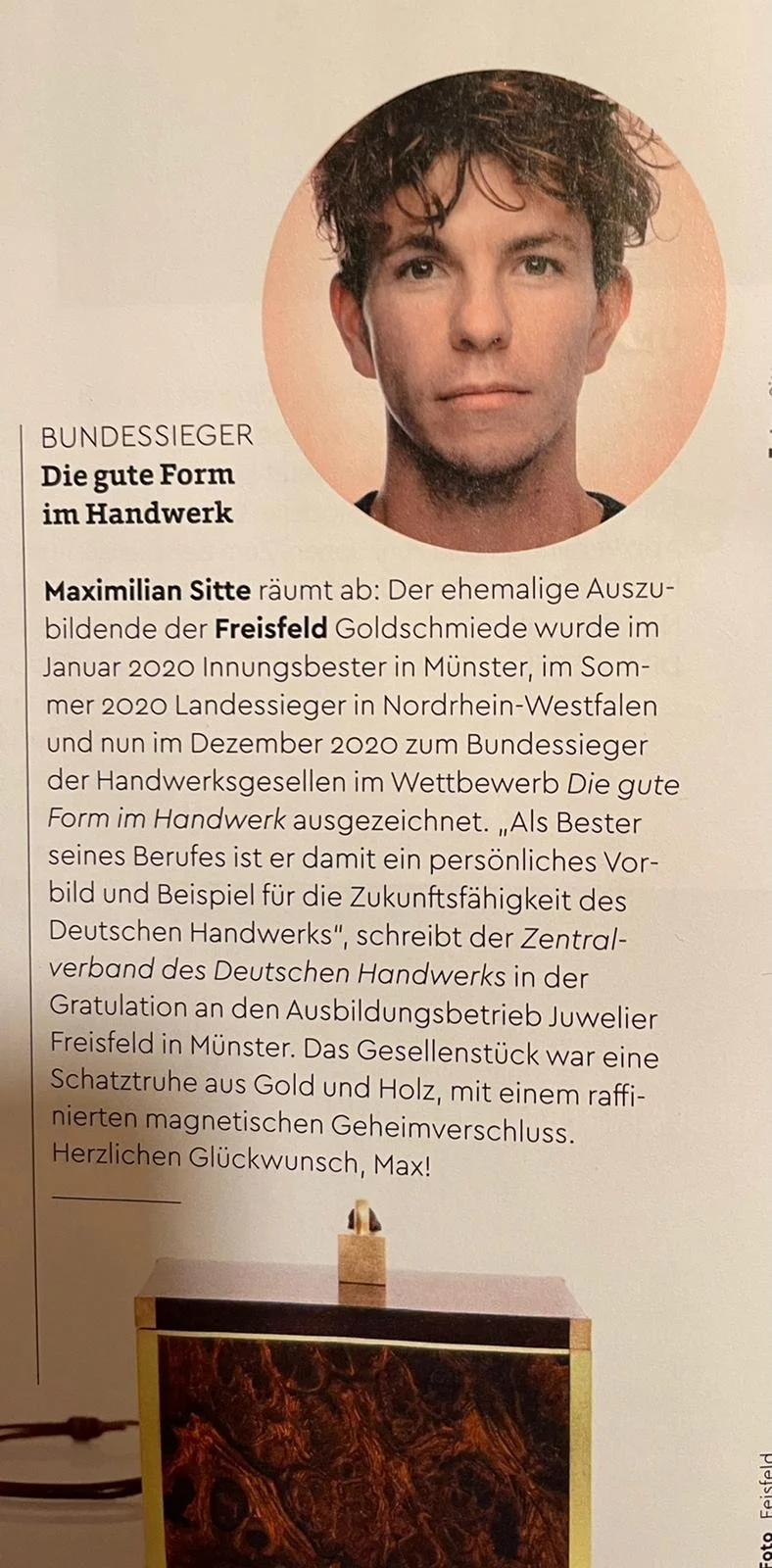 Portrait von Maximilian Sitte mit dunklen, lockigen Haaren, oberhalb eines Textes und eines Schmuckstücks aus Gold und Holz.