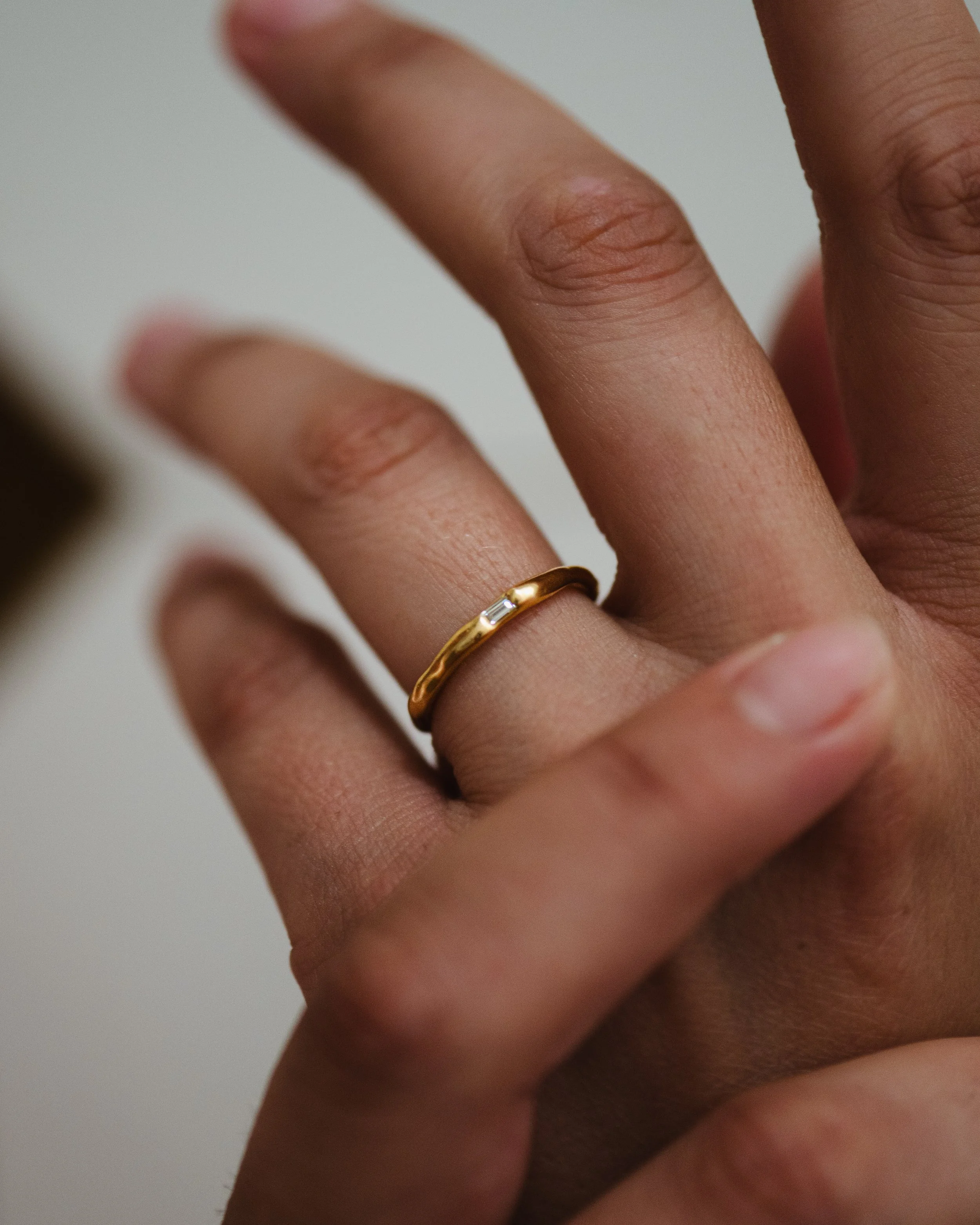 Nahaufnahme einer Hand mit einem goldenen Ring am Ringfinger.