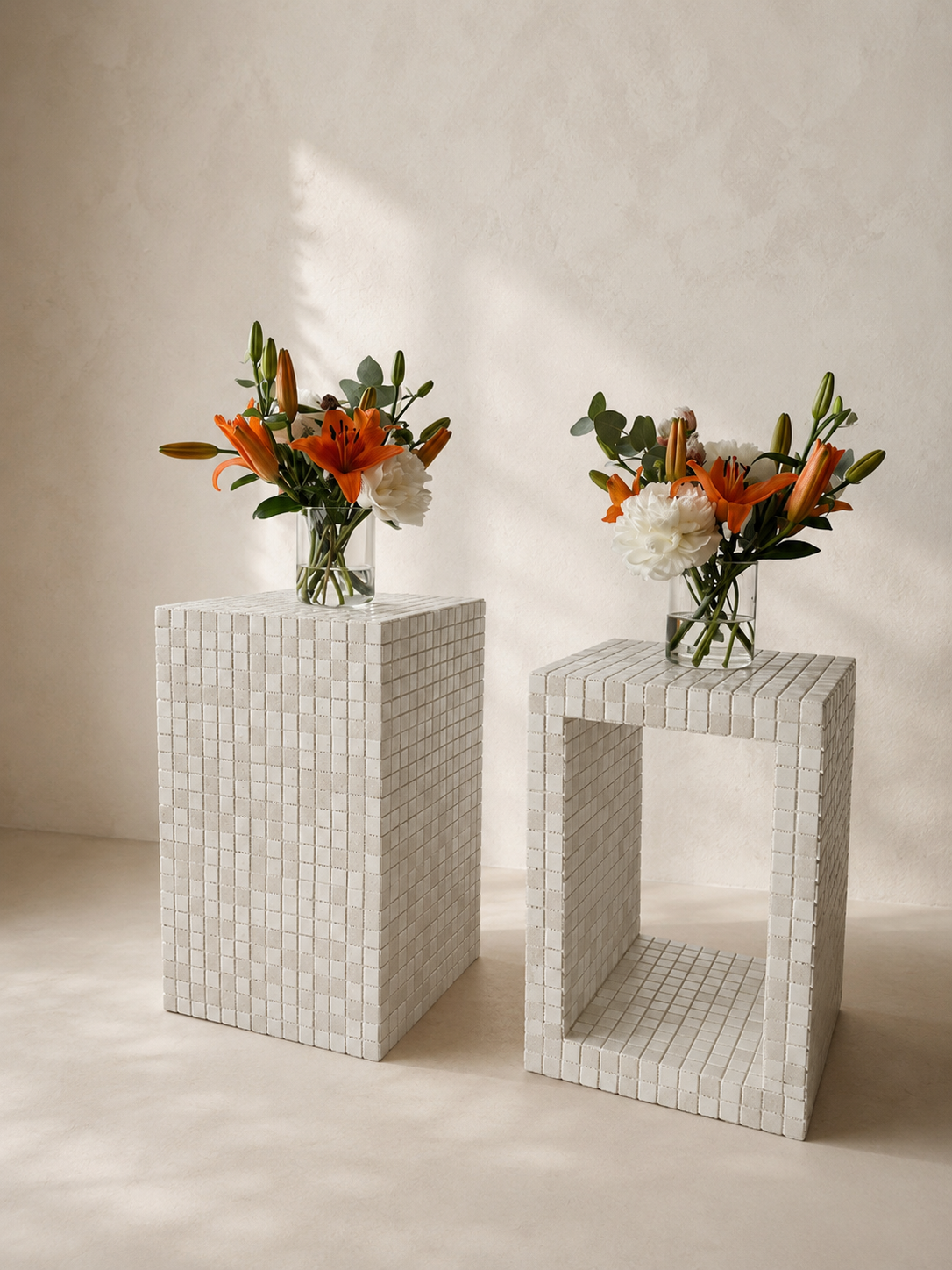 Bespoke handmade ceramic objects with glass vases of lilies, white flowers, and green foliage against a neutral background.