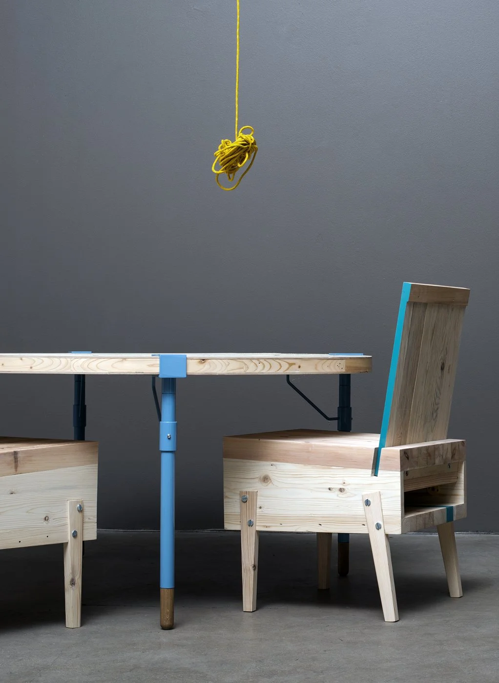 Minimalist wooden table and chairs with blue accents, hanging yellow cable.