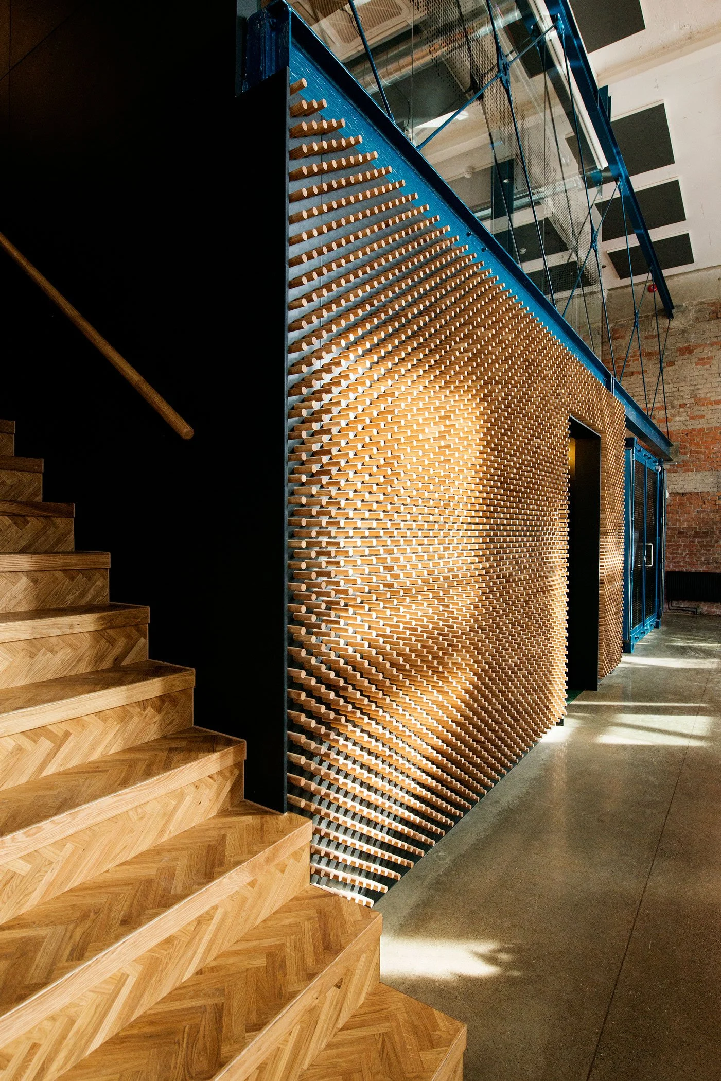 Interior design with wooden stairs and a unique textured wall made of protruding wooden pegs, industrial style with exposed ceiling and polished concrete floor.