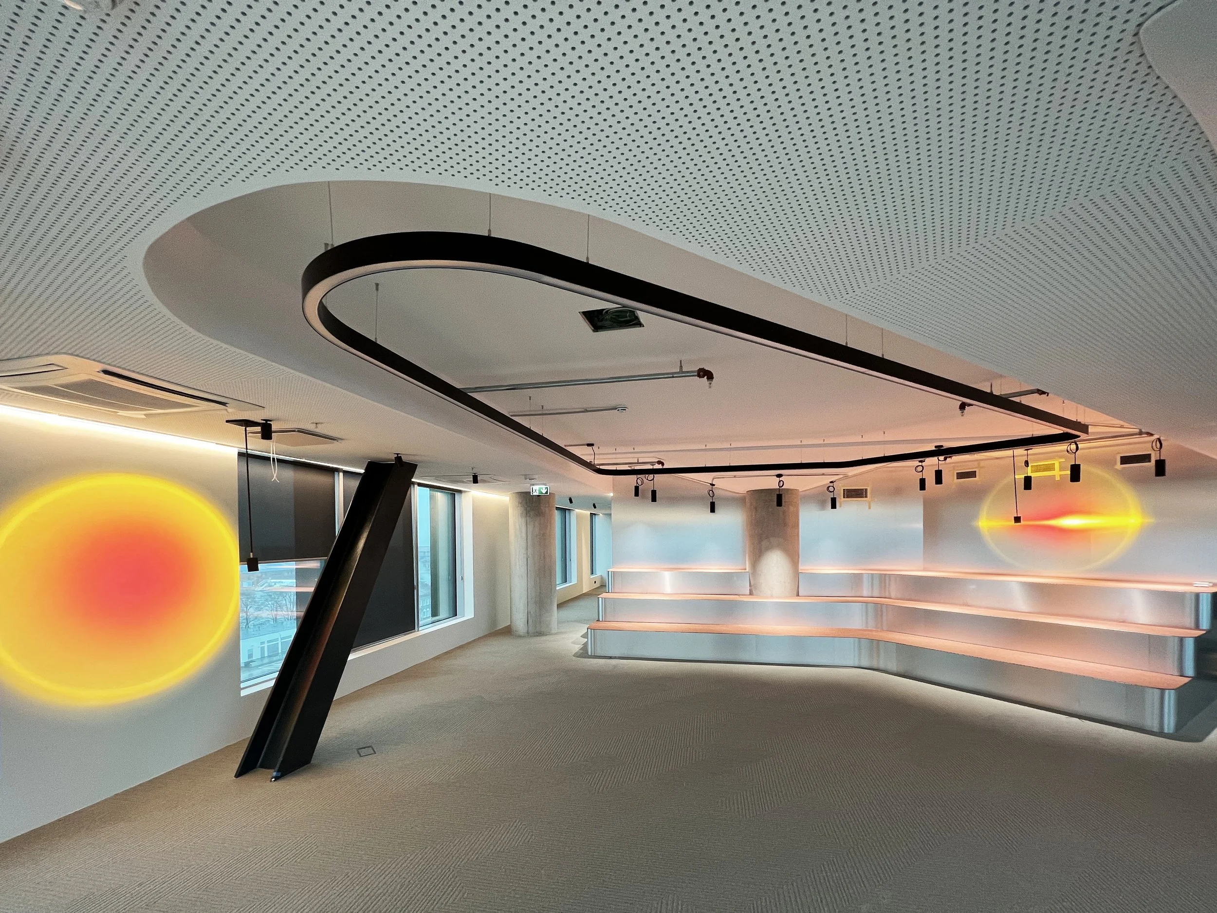 Modern office space with curved ceiling, artistic lighting, and decorative wall features.