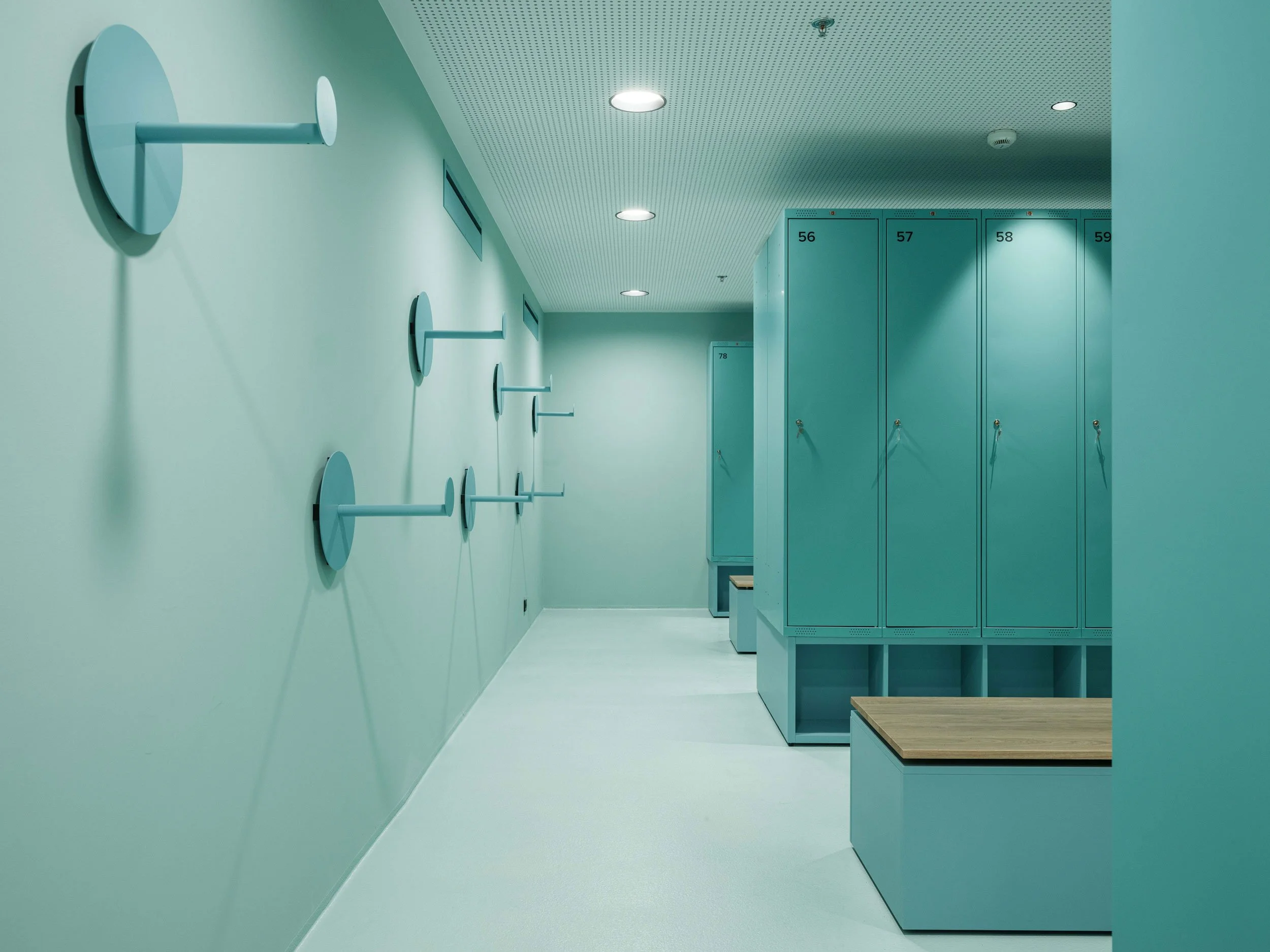 MUBA Modern locker room with teal lockers and benches by Tõnis Kalve and T43 Interior Architects
