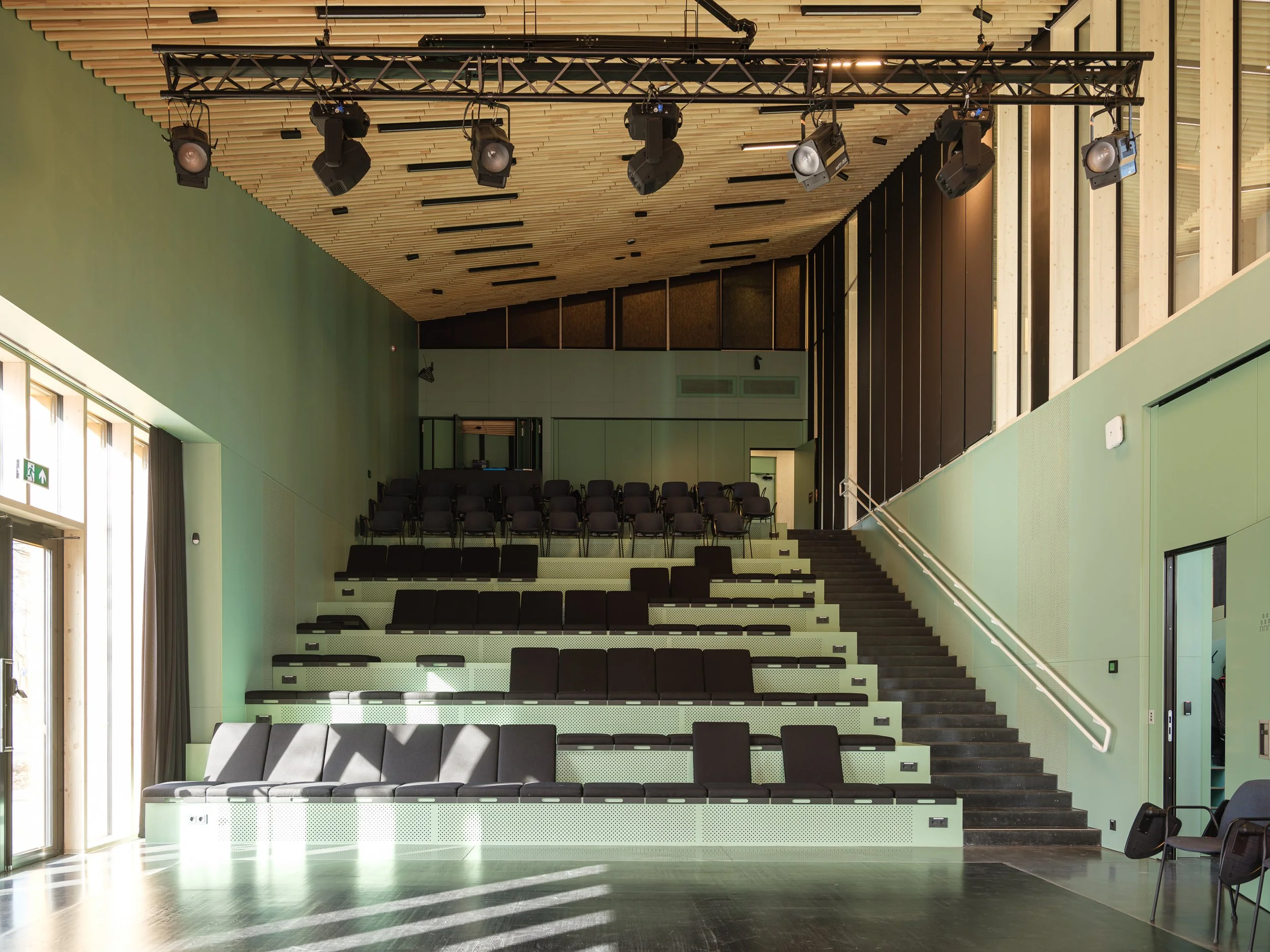 Interior of an empty auditorium with tiered seating and stage lights.