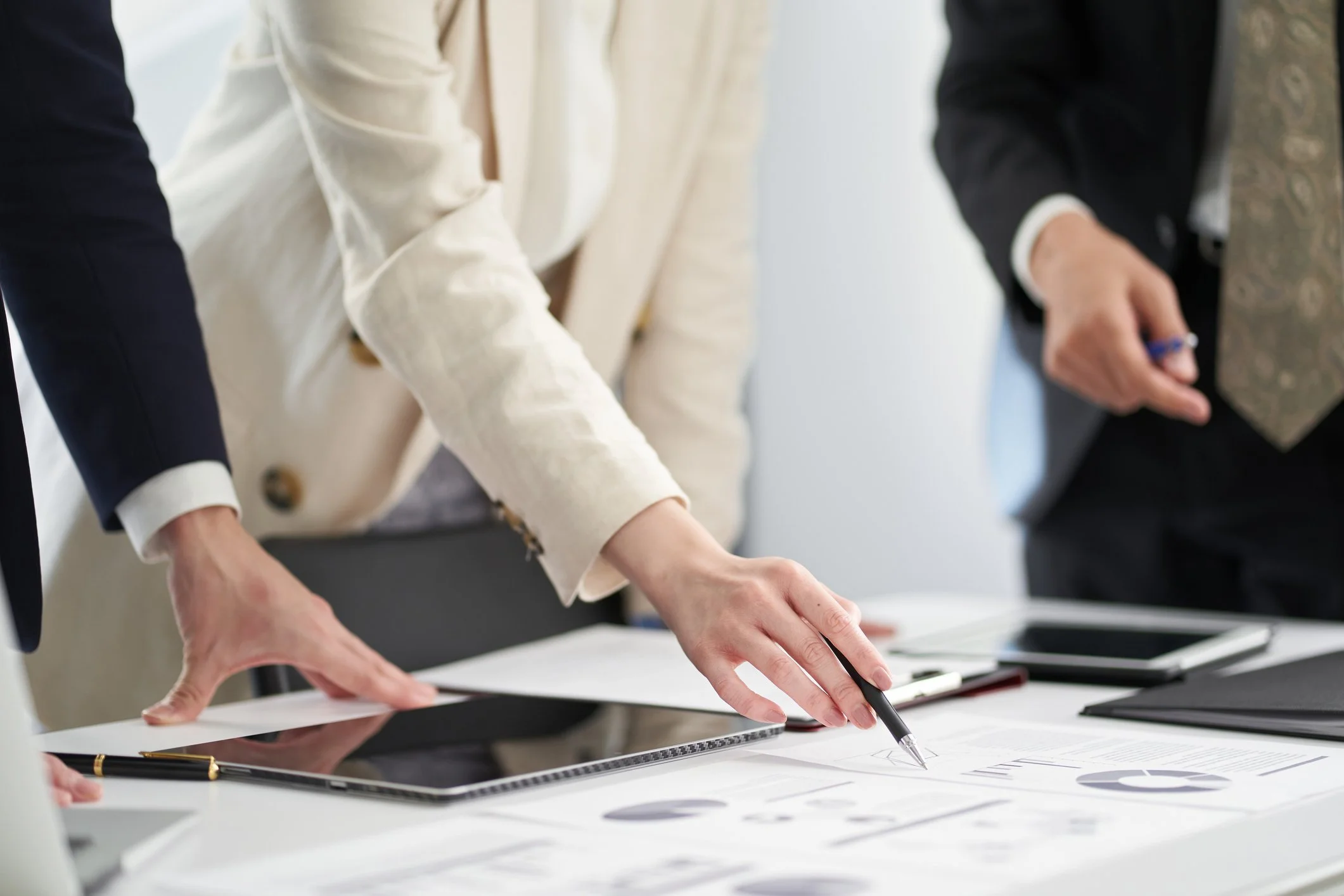 Menschen diskutieren um einen Tisch mit Dokumenten, Tablets und Smartphones in einem Büro.