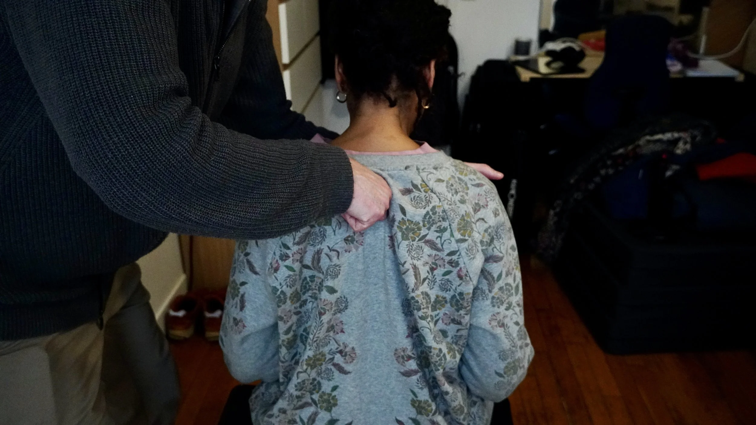 Person receiving a shoulder placement as part of SpineTuned practice from another person indoors