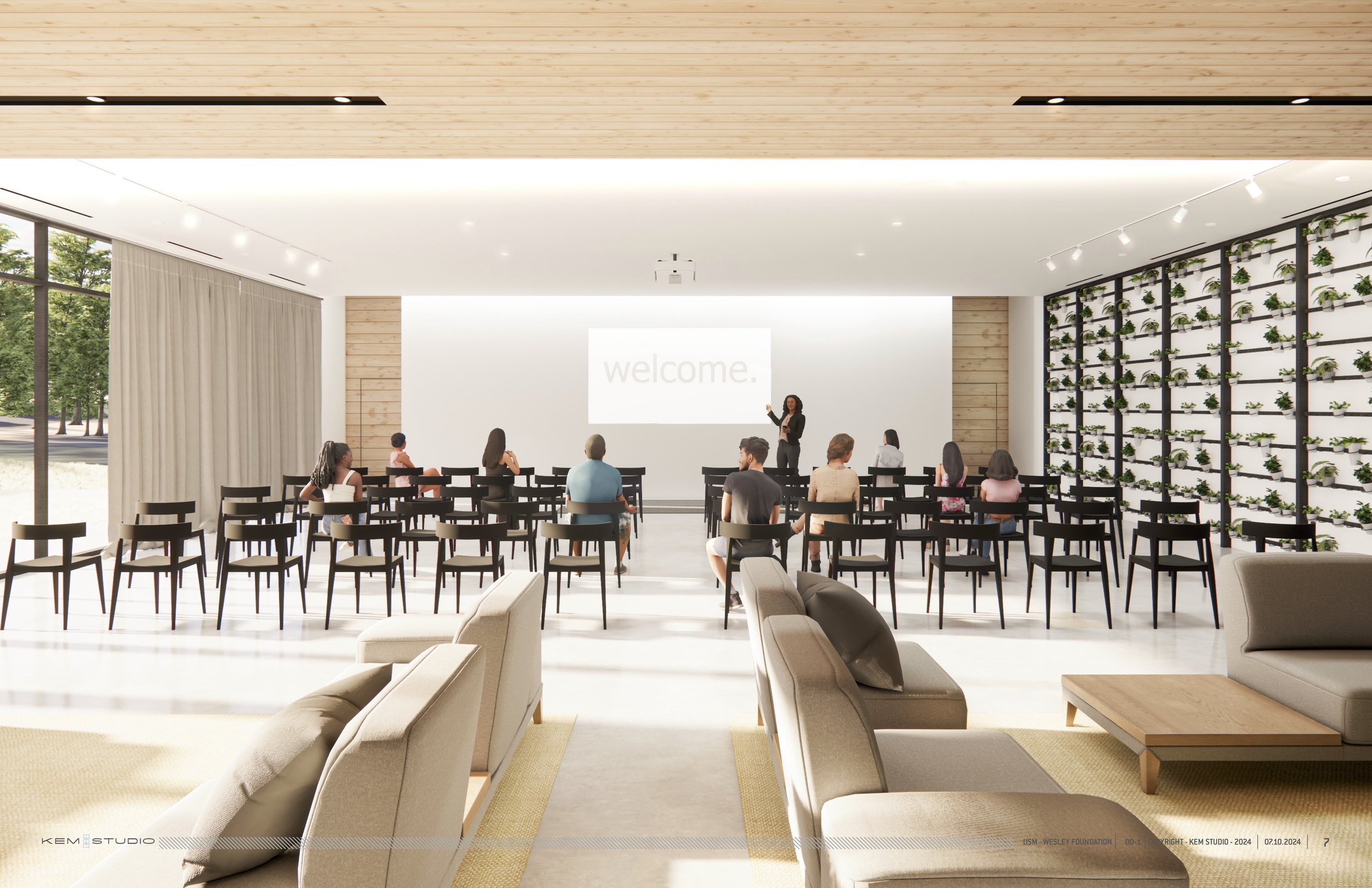 Interior of a modern conference room with people seated, a presenter at the front, and a large screen displaying 'welcome'. The room has wooden ceilings, plant wall, and large windows.