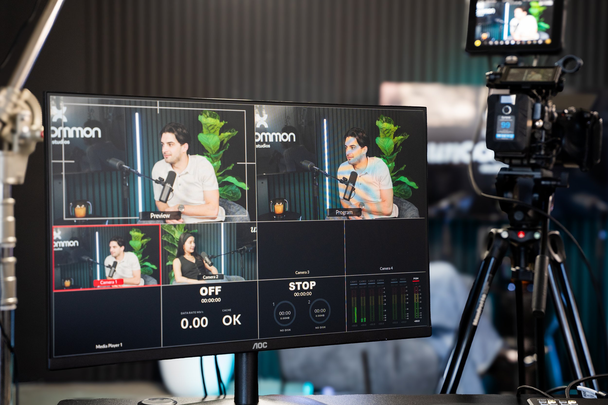 Multi-camera podcast setup with live feed display on a monitor showing two speakers in a studio.