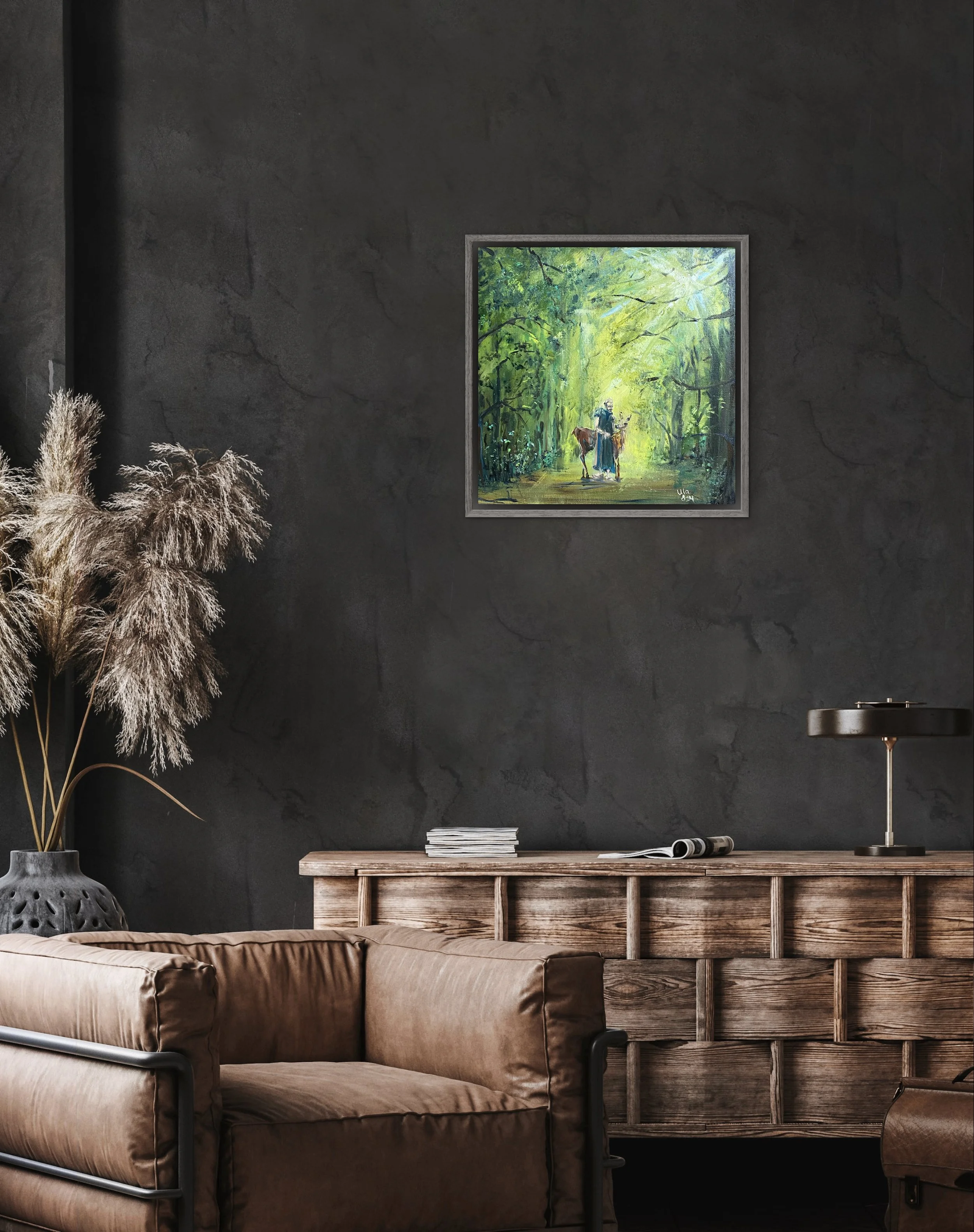 Ein Wohnzimmer mit dunkler Wand, einer Couch aus braunem Leder, einem Holztisch, einer schwarzen Tischlampe und einem Bild eines Waldwegs mit einer Figur auf einem Pferd.