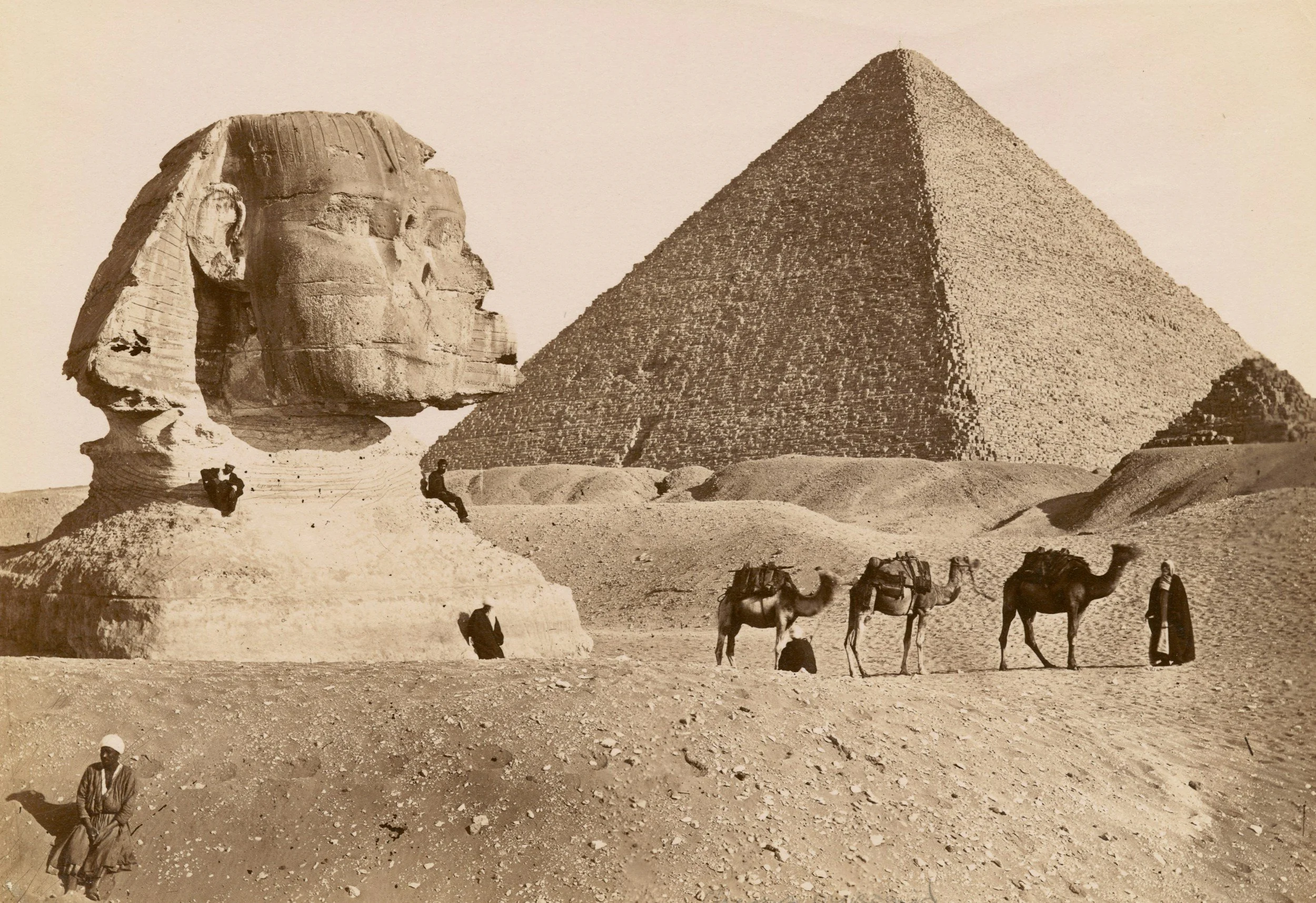A sepia-toned photograph of the Sphinx and the Great Pyramid of Giza in Egypt. The Sphinx's face and body are visible on the left, with a seated figure nearby. In the background, the pyramid towers over the desert landscape. History tutor