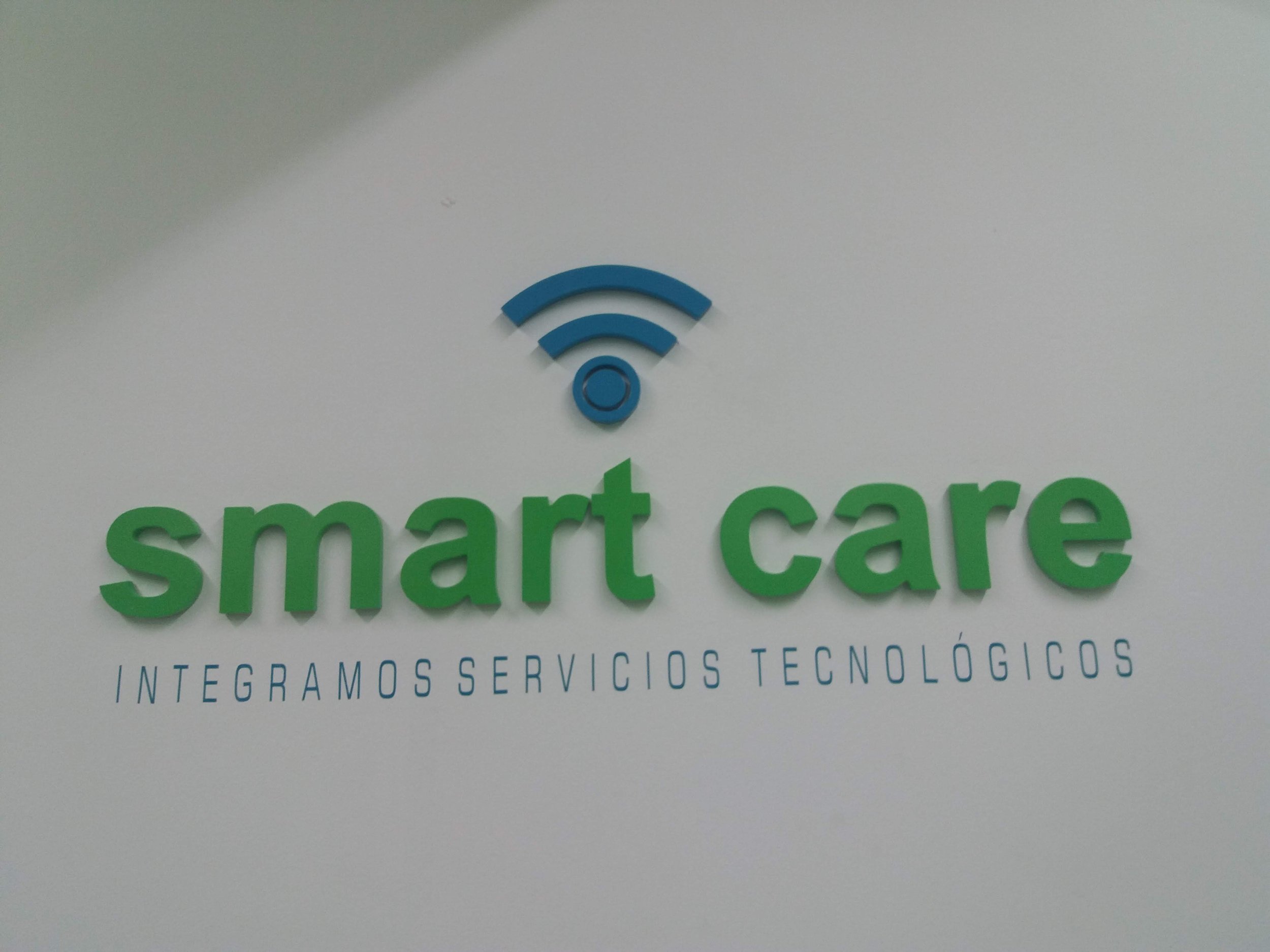 Logotipo de "smart care" con símbolo de Wi-Fi y texto "INTEGRAMOS SERVICIOS TECNOLÓGICOS" en la pared.