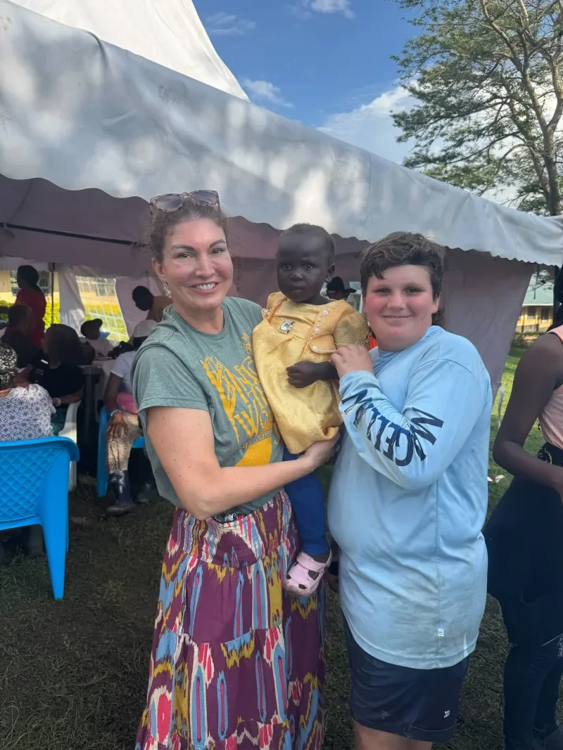 Life For Children Ministry mission team members posing with a Kenyan orphan child