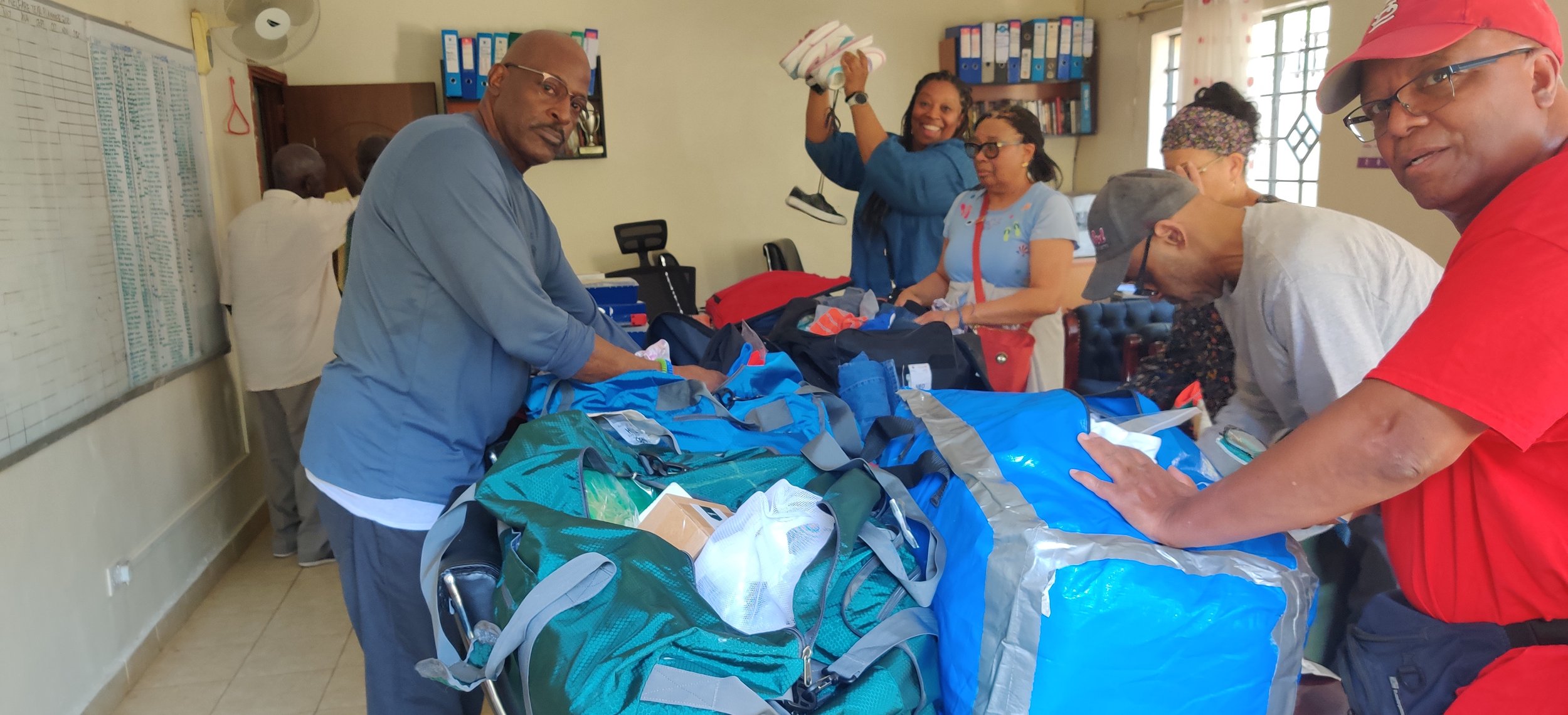 Group of people organizing supplies in a room with bags and binders visible.