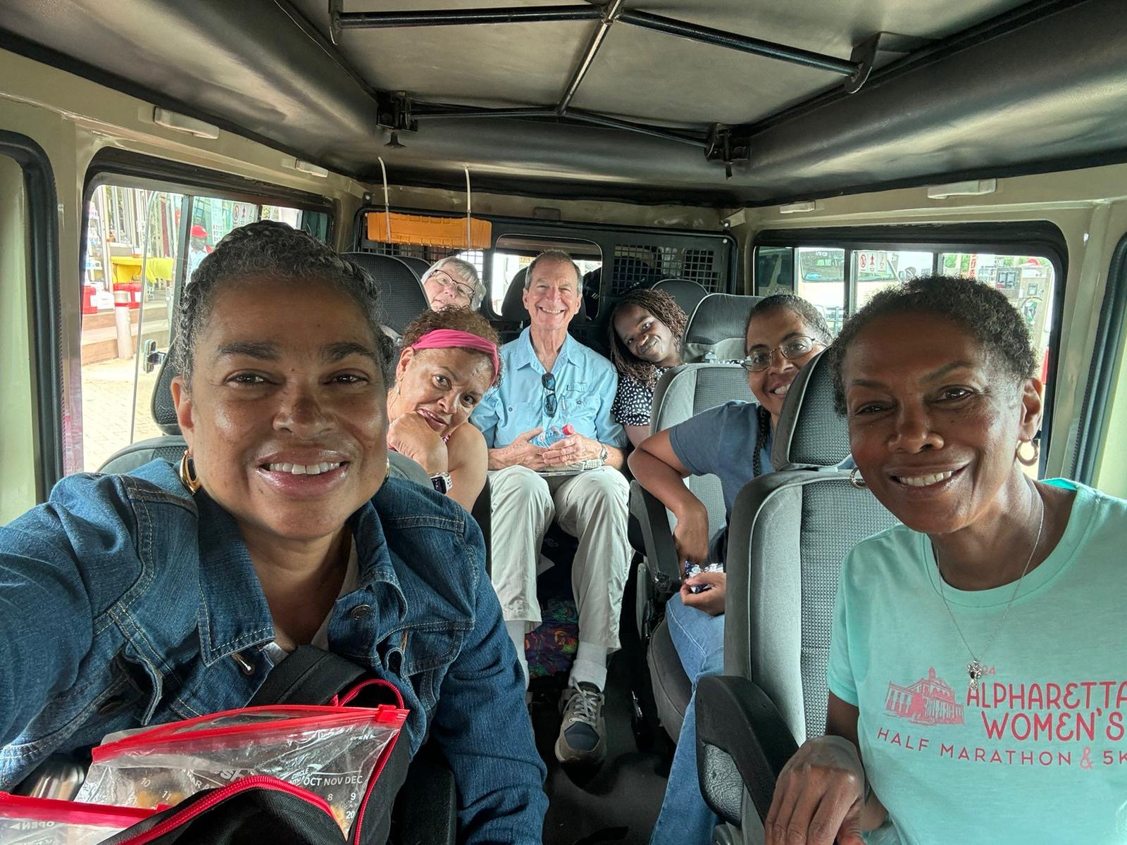 A group of smiling people sitting inside a van.