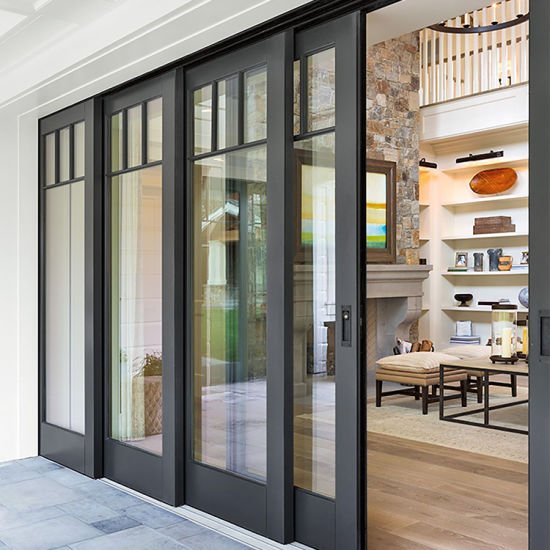 Modern sliding glass doors leading to a stylish living room with a stone fireplace and bookshelves.