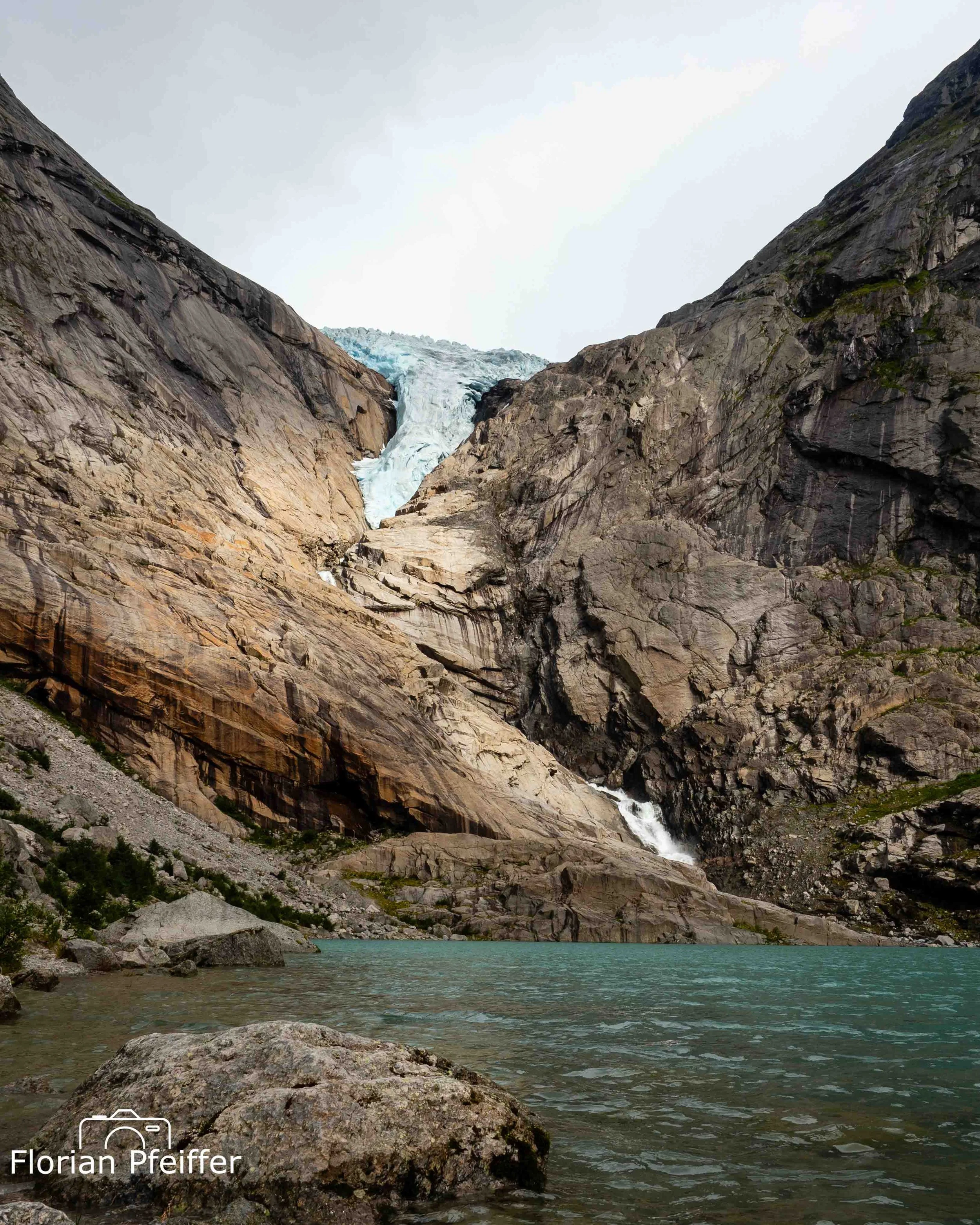 Glacier view from a lake with a rock in foreground.