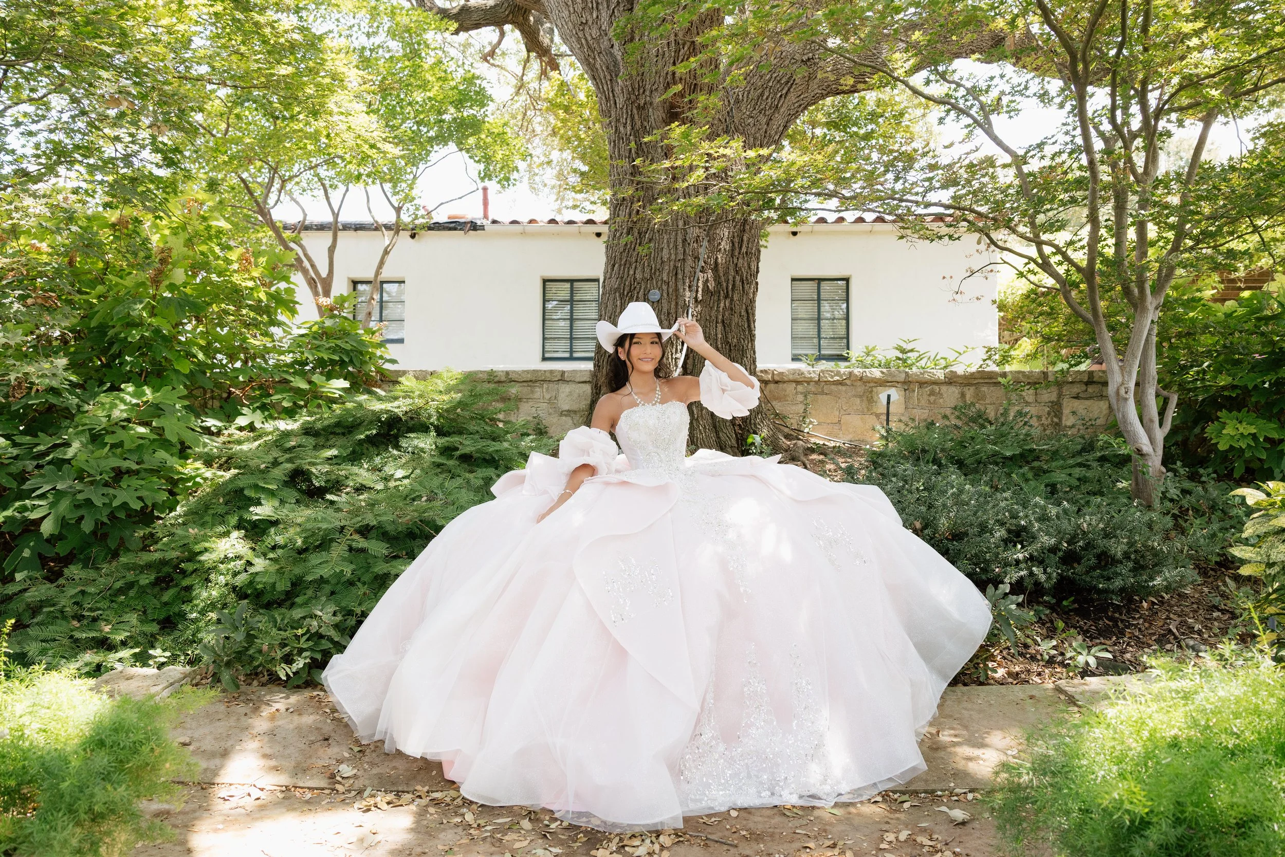 Quinceañera in a white gown and cowboy hat during an outdoor DFW portrait session