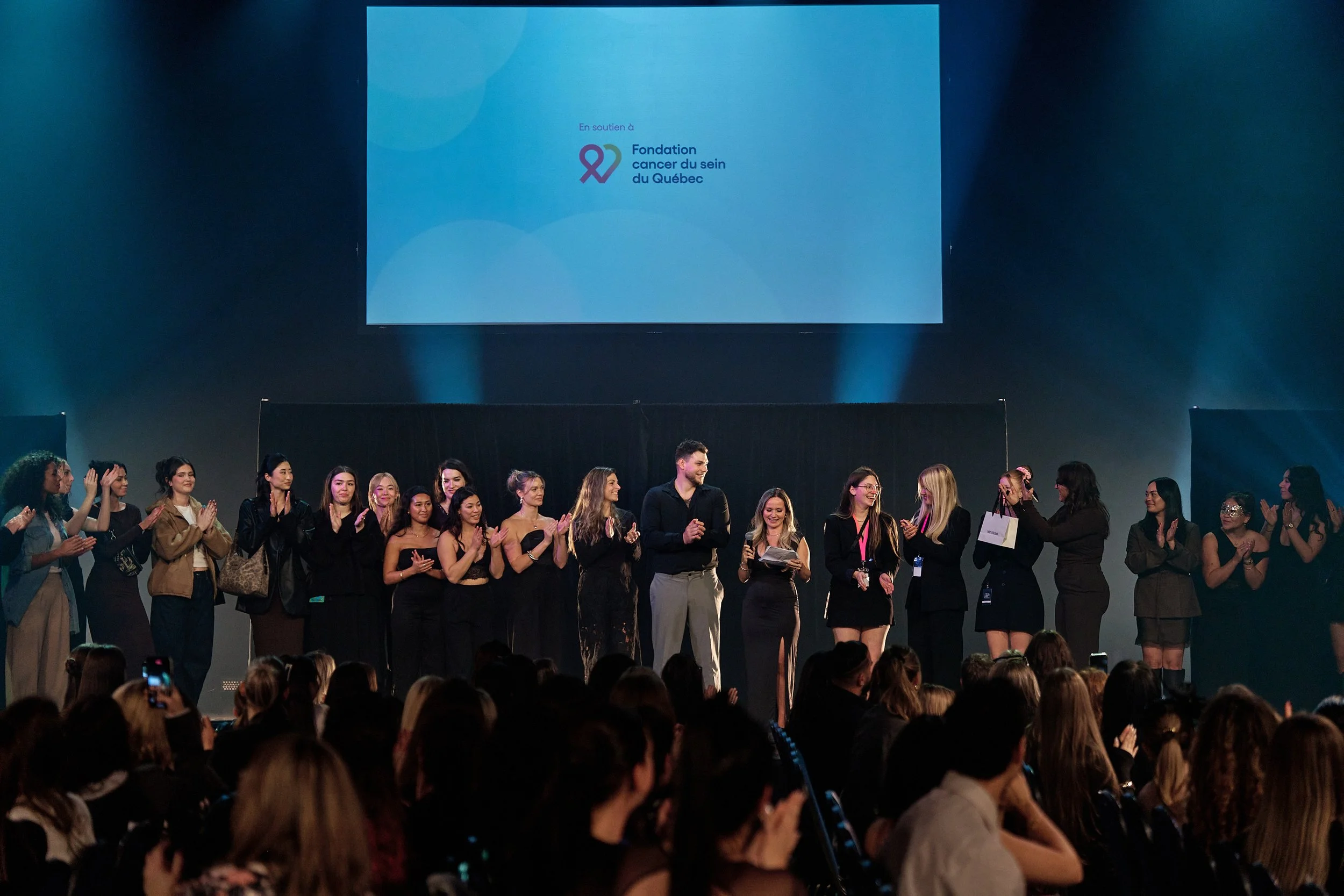 L’équipe du Défilé Masqué 2025 réunie sur scène au Théâtre Paradoxe, applaudissant la réussite de l’événement au profit de la Fondation du cancer du sein du Québec.