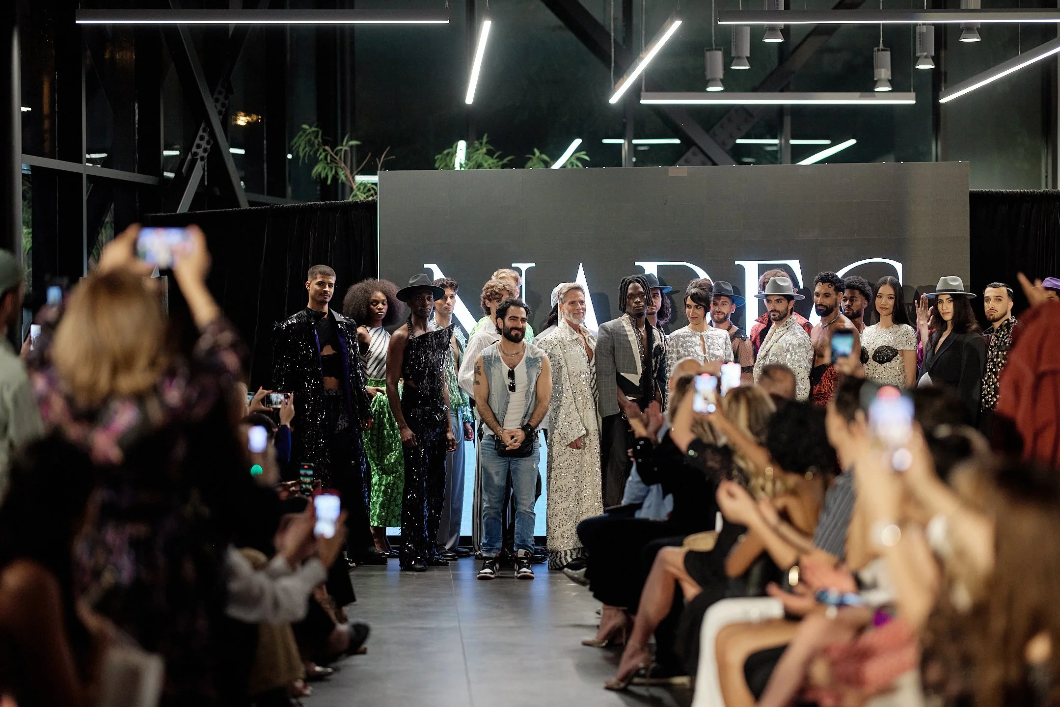 Finale du défilé M3 Montréal 2025: les mannequins et le designer saluent le public, présentant une diversité de silhouettes, de textures et de styles, sous les projecteurs du showroom Lamborghini.