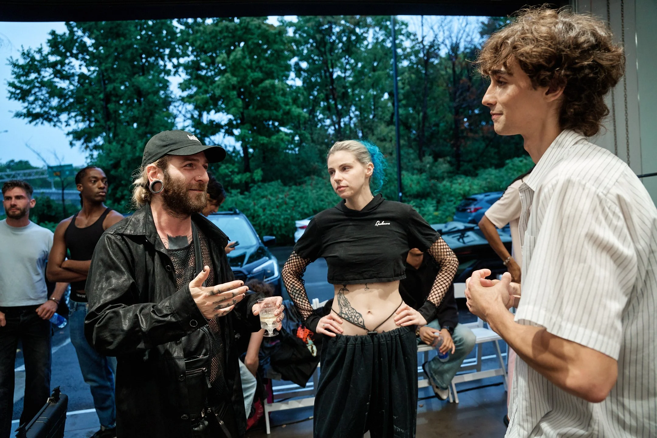 Backstage du défilé M3 Montréal 2025: échange entre les membres de l’équipe créative de Guillaume Chaigne, capturant un moment de préparation et de réflexion avant la présentation des silhouettes sur le podium.