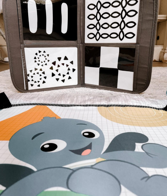 A baby playmat on a living room floor for working on tummy time and motor control.