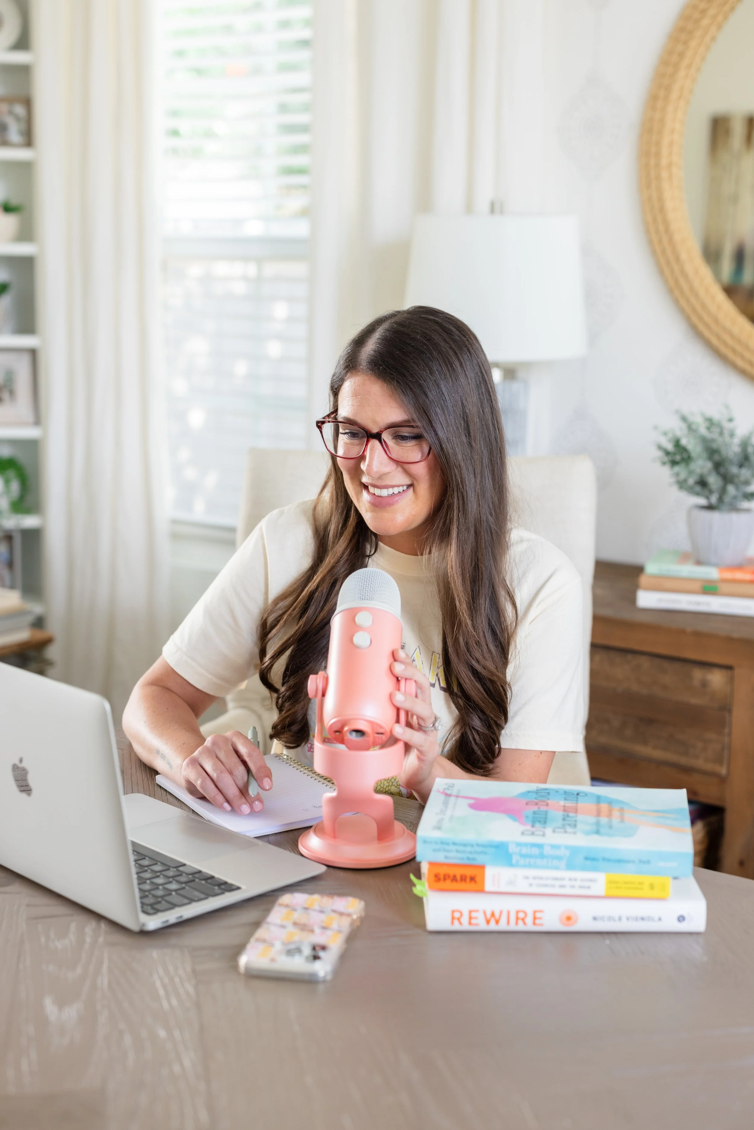 Erin Clarelli uses a pink microphone to chat with guests on her Autism podcast.