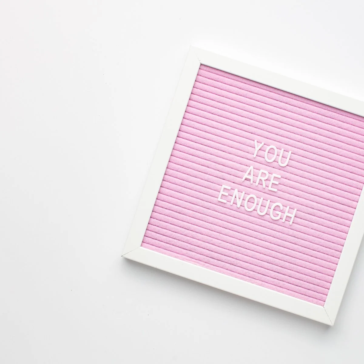 A pink and white sign with the words, "You Are Enough".