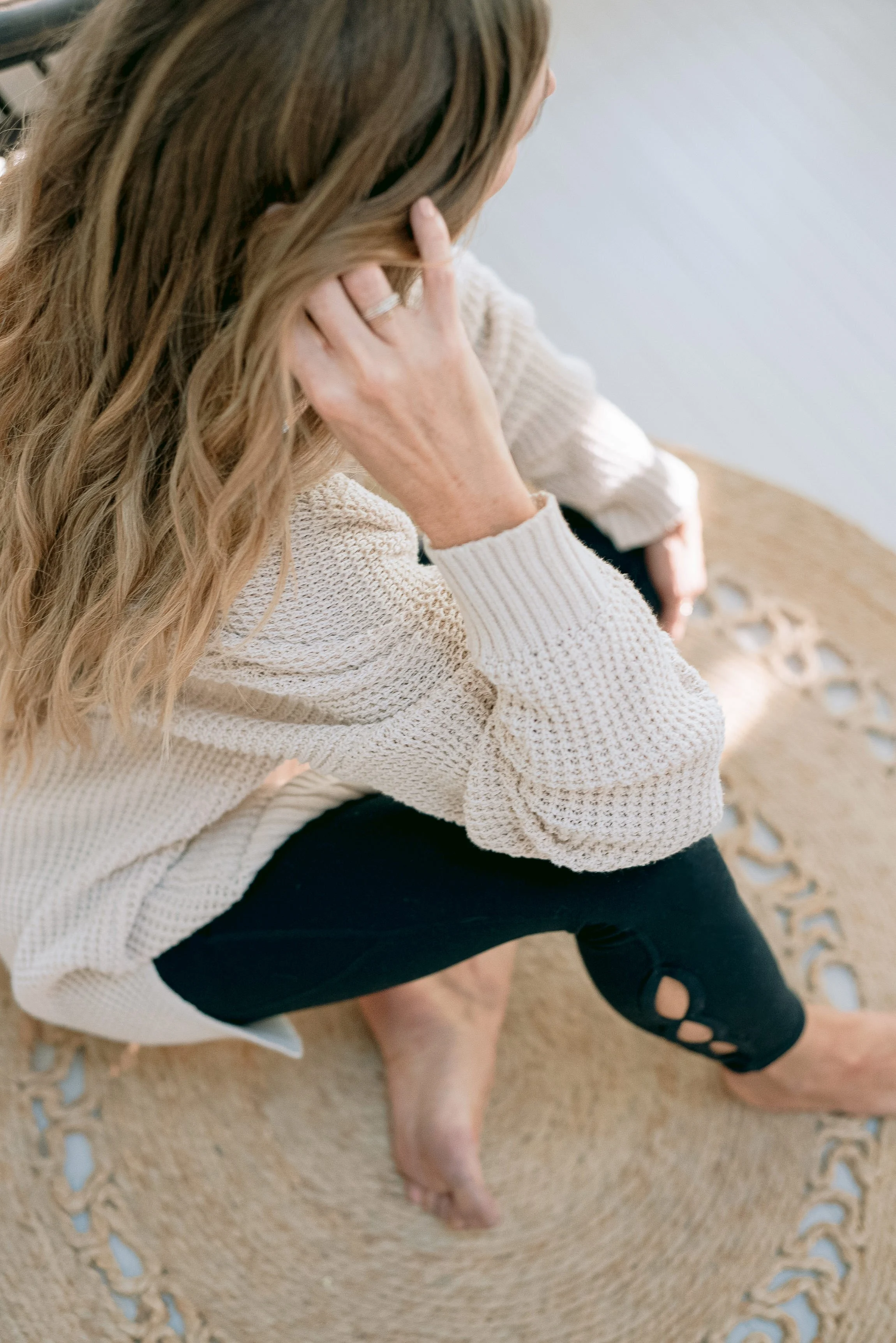 Woman seated with hand resting near collarbone, illustrating calm body awareness and regulation.