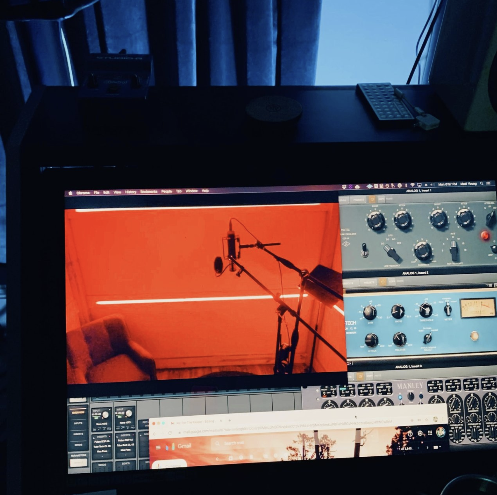 Computer monitor displaying a music production software interface and a photo of a microphone recording setup with a red background.
