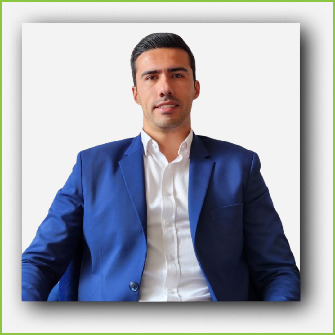 A man wearing a white shirt and a blue blazer, sitting against a plain background.