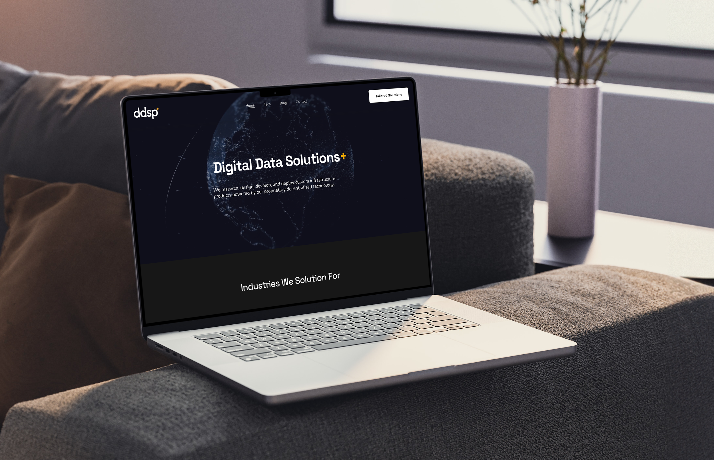 Open laptop on a gray couch displaying a website titled 'Digital Data Solutions' with a world map graphic.