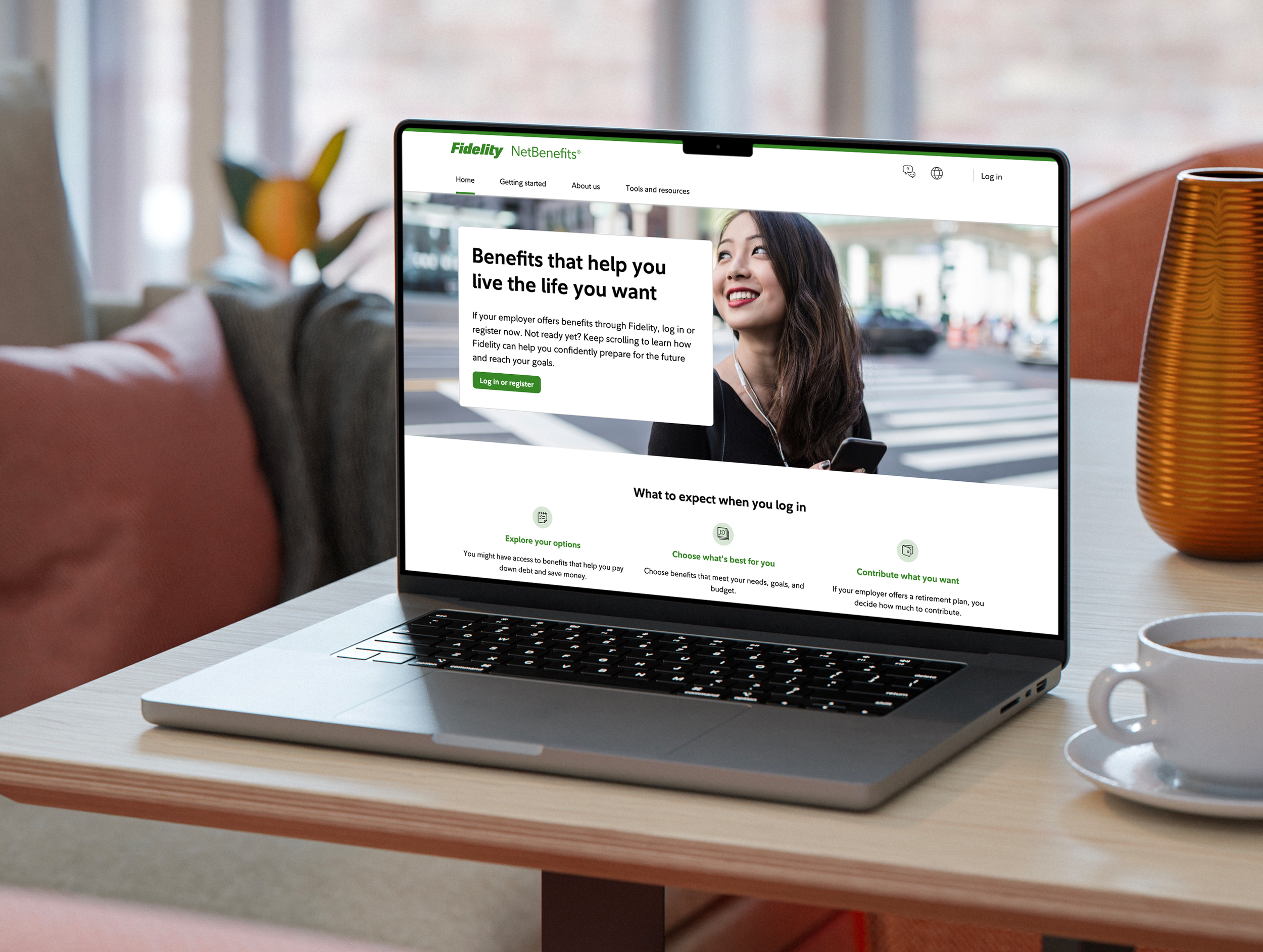 Laptop on a table displaying a webpage for Fidelity NetBenefits, featuring a woman smiling and walking outdoors, with menu options and informational sections visible on the screen.
