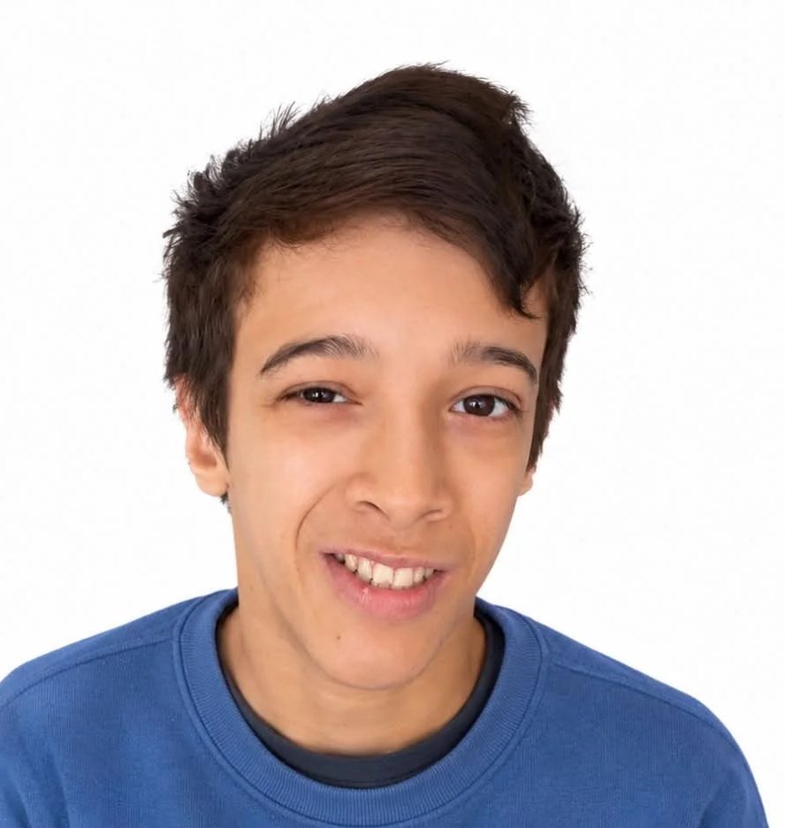 A young man with medium-length brown hair, wearing a blue shirt, smiling slightly and winking, against a plain white background.