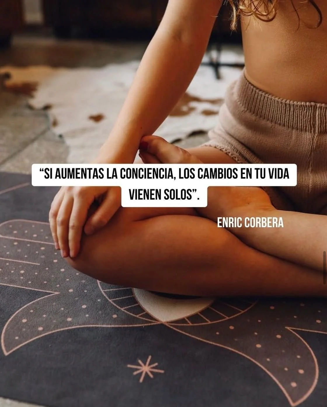 Una persona en posición de meditación con una frase motivacional en español, en un fondo de suelo de cerámica y una manta con diseño geométrico en tonos oscuros y rosados.