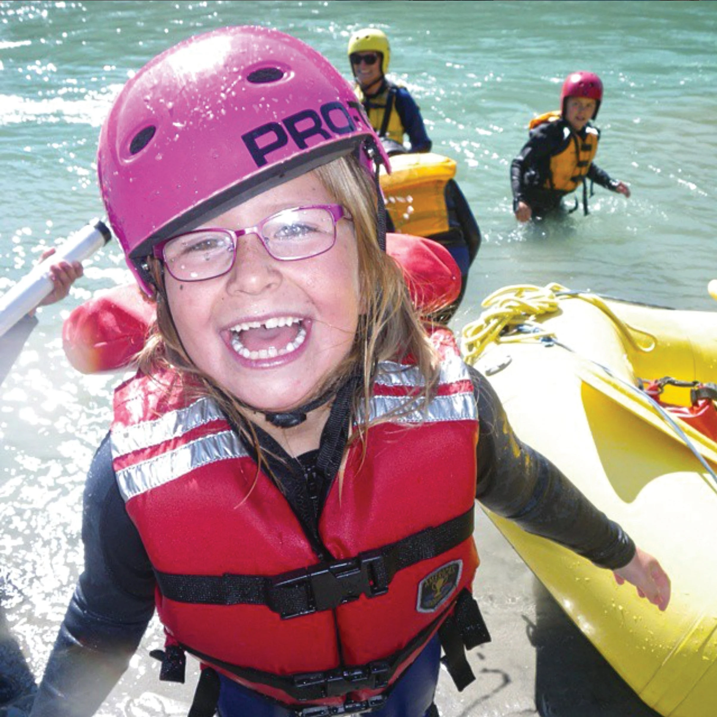 Enfant souriant lors d’une sortie rafting en famille en Norvège avec bataille d’eau sur la rivière glaciaire de Jostedal.