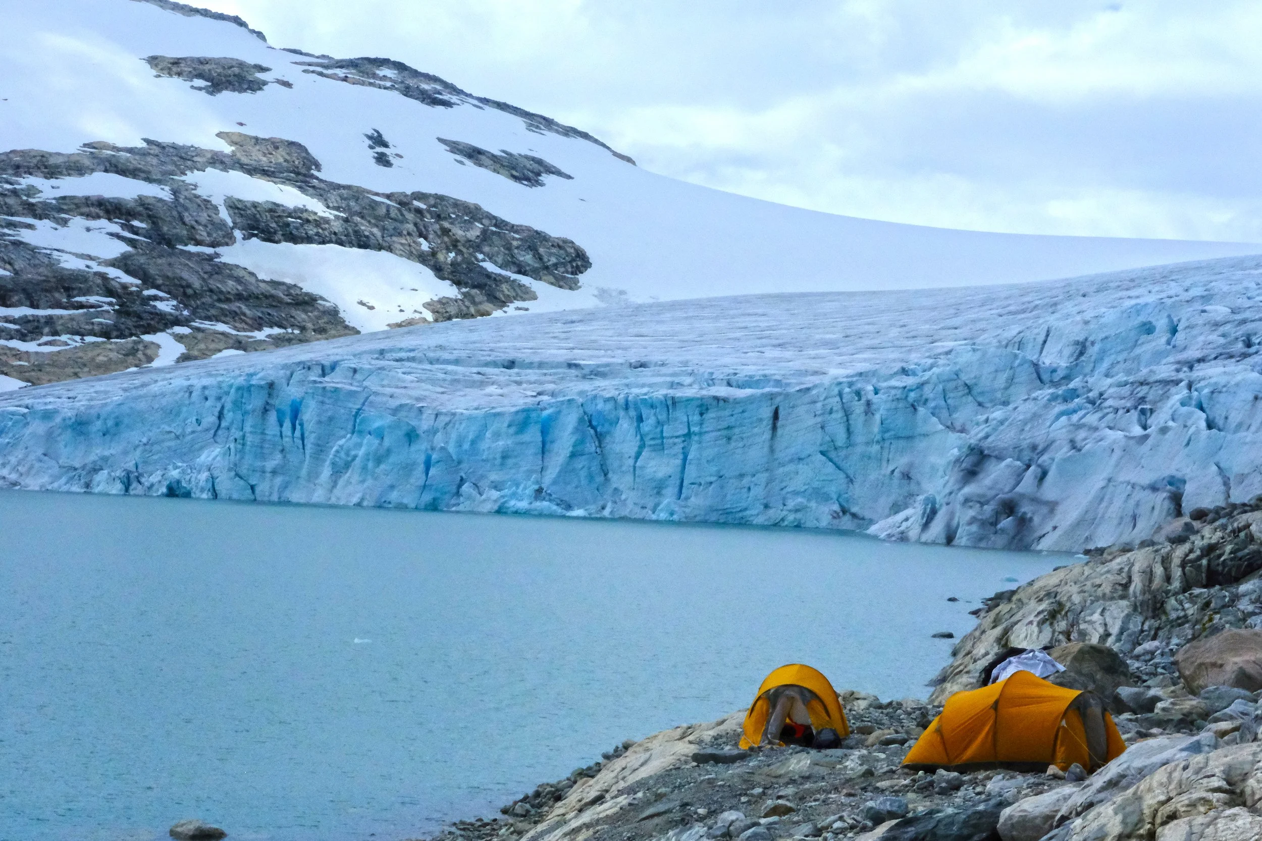 Glacier camping beside Styggevatnet with tents and the calving front of Austdalsbreen in Jostedalsbreen National Park, Norway.