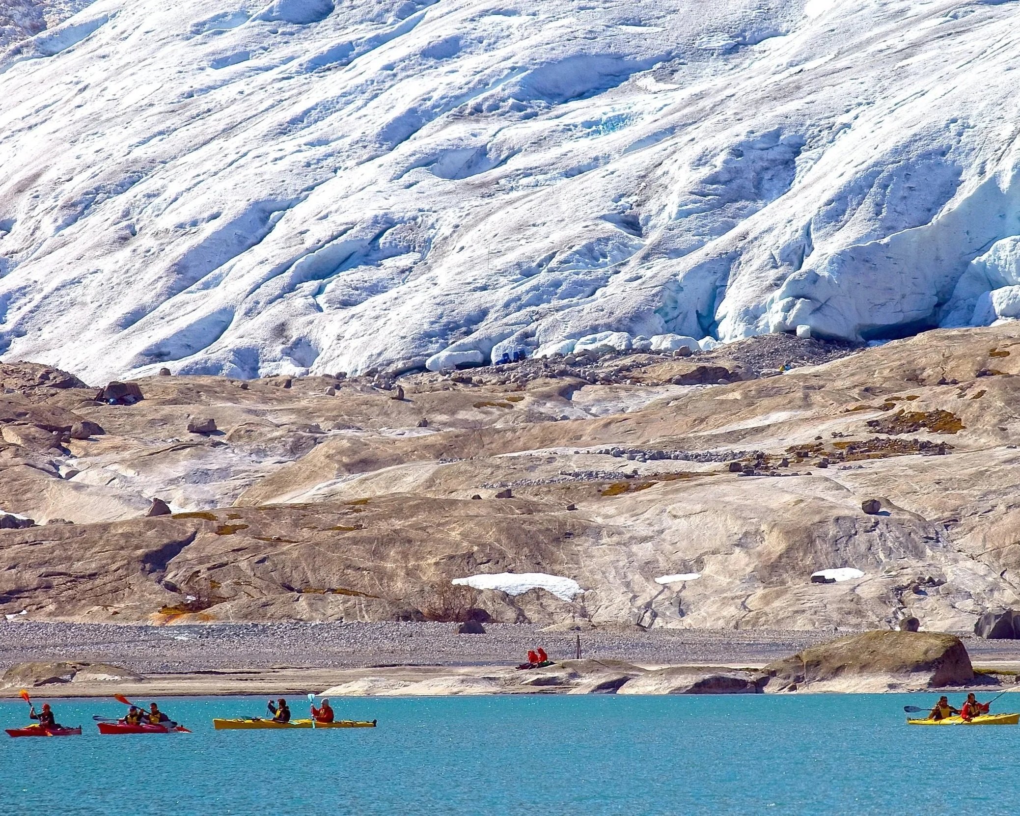 Kayaks on Nigardsbrevatnet heading toward Nigardsbreen glacier on a sunny day in Jostedalsbreen National Park, Norway.