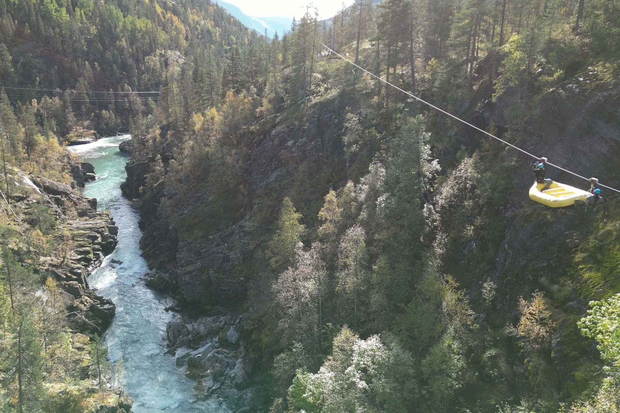 Zipline with raft suspended above a glacier river canyon in Norway during a guided adventure tour.
